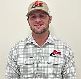 A man wearing a plaid shirt and a hat is smiling for the camera.