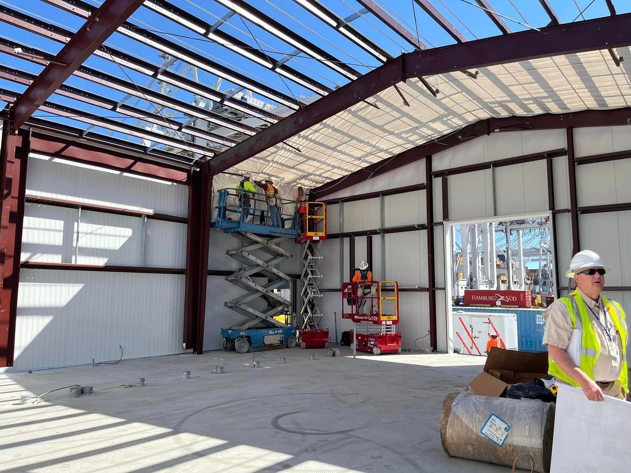 A man in a hard hat is standing inside of a building under construction.