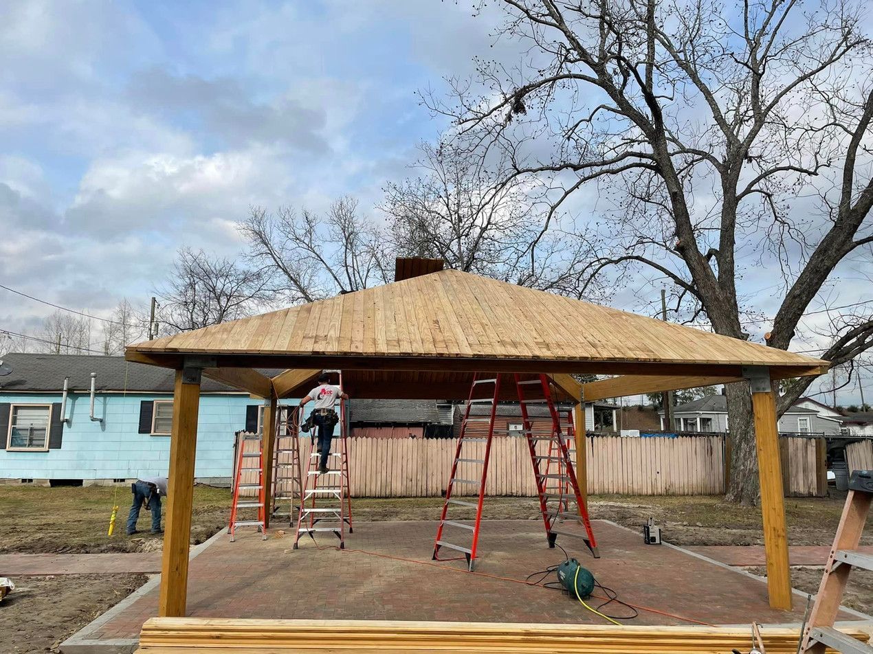 A gazebo with a thatched roof is being built in a backyard.