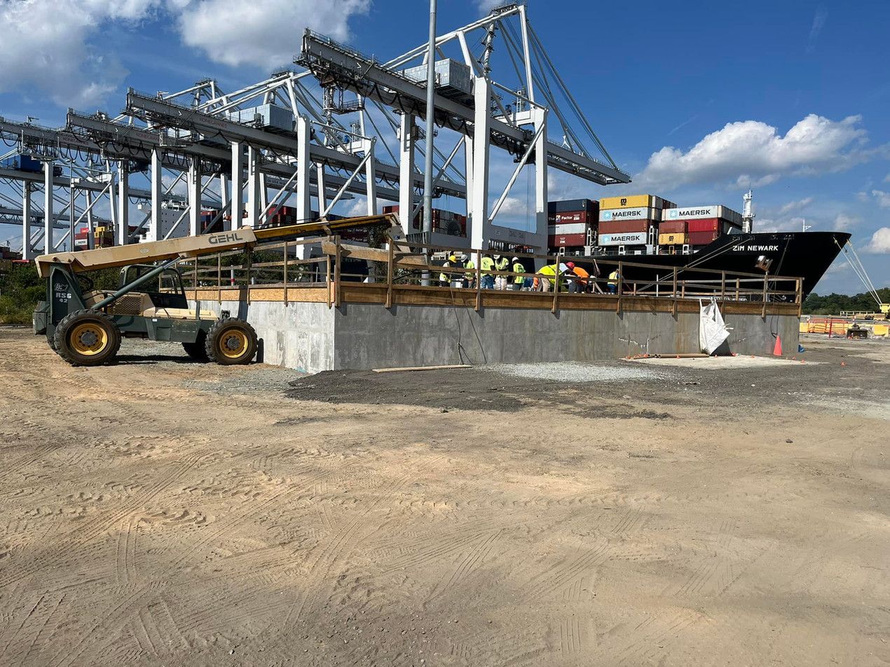 A construction site with a large ship in the background.