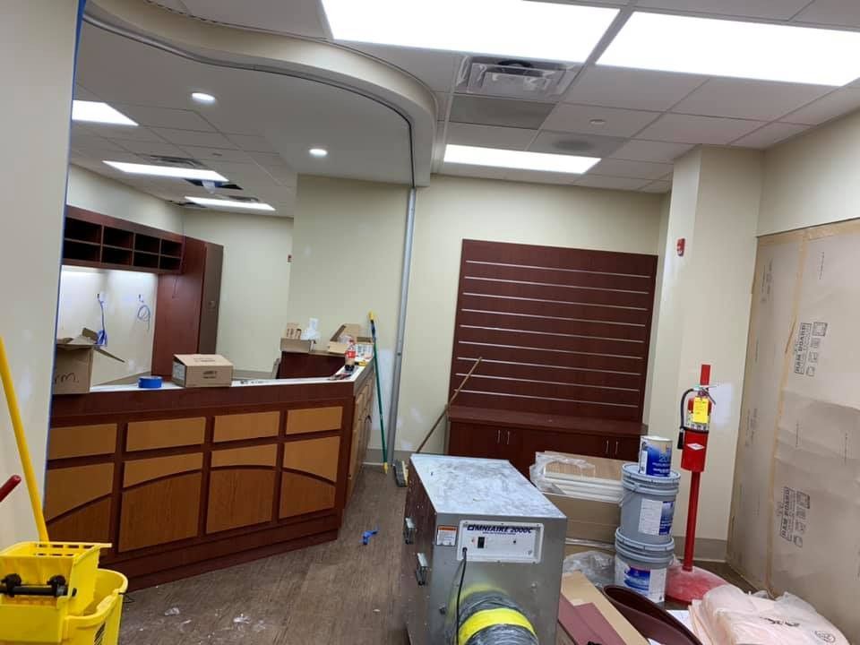 An empty room with a yellow mop and a fire extinguisher.