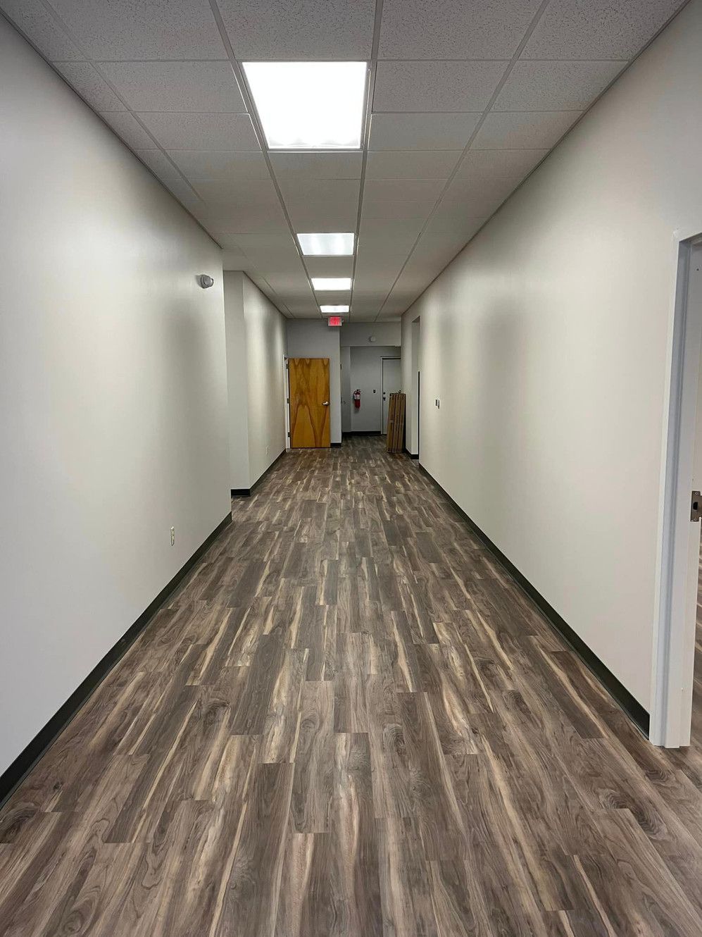 A long hallway with a wooden floor and white walls.