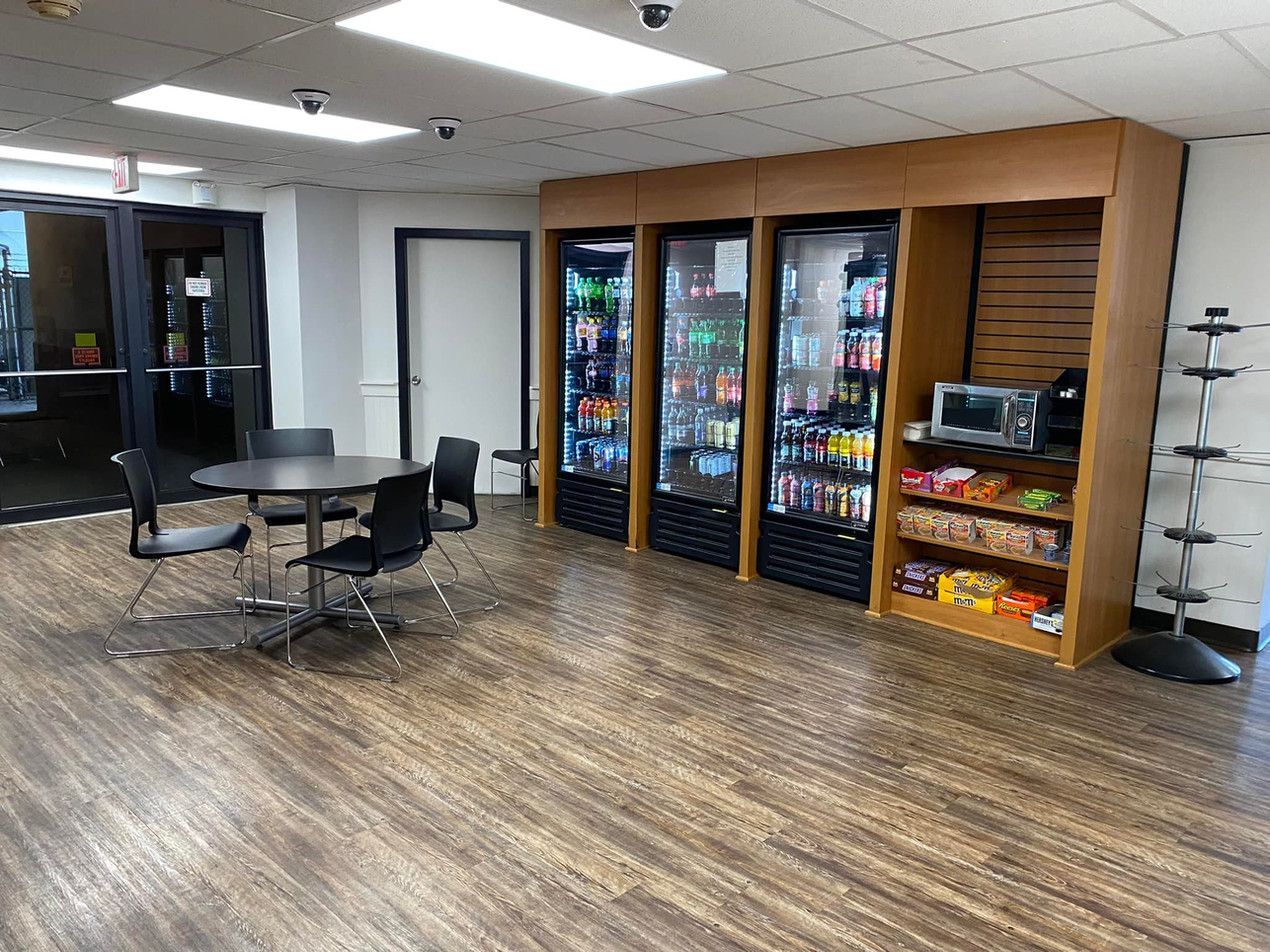 A room with a table and chairs and a bunch of refrigerators.