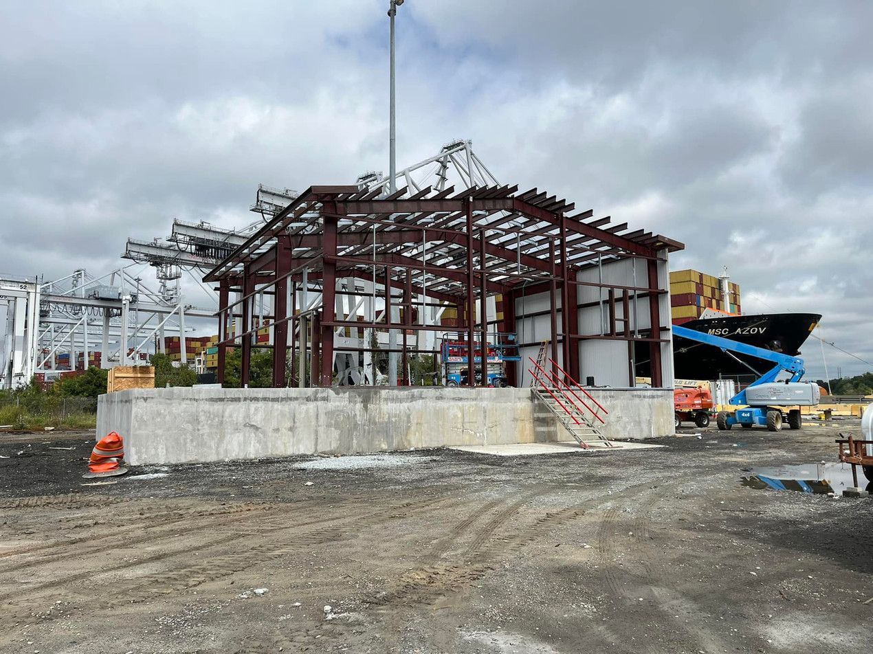 A large metal structure is being built in a dirt field.