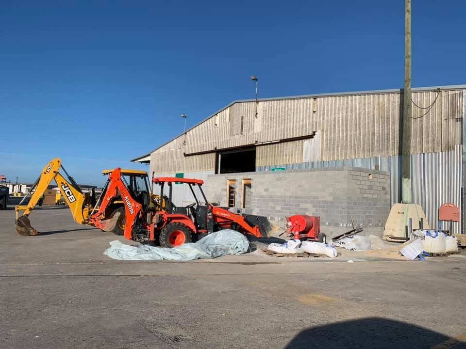 A yellow and orange tractor is parked in front of a building
