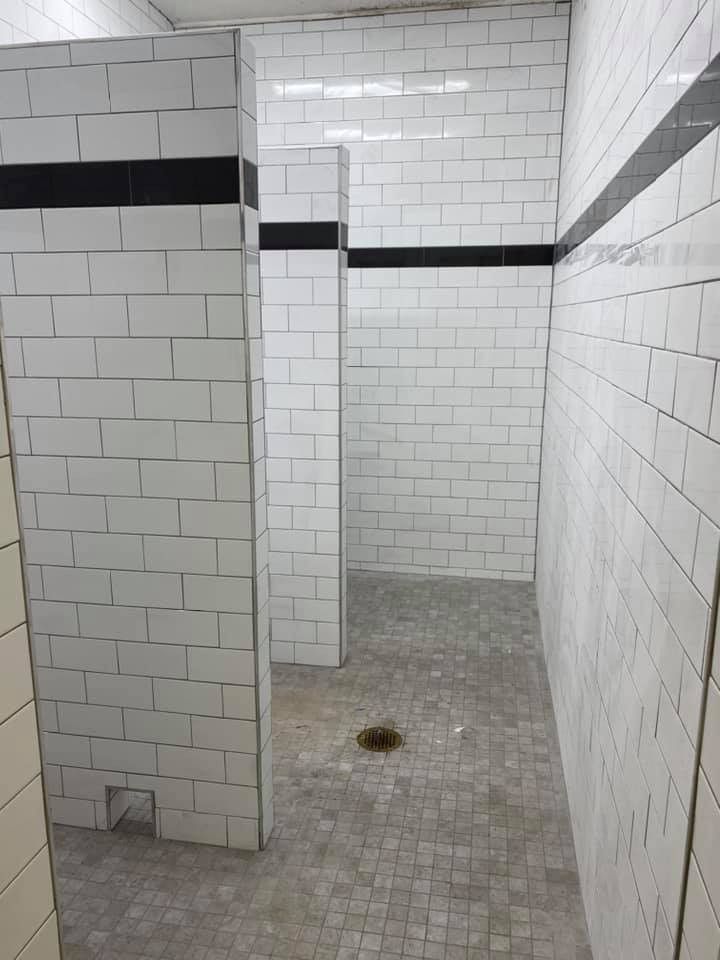 A bathroom with white tiles and black stripes on the walls.