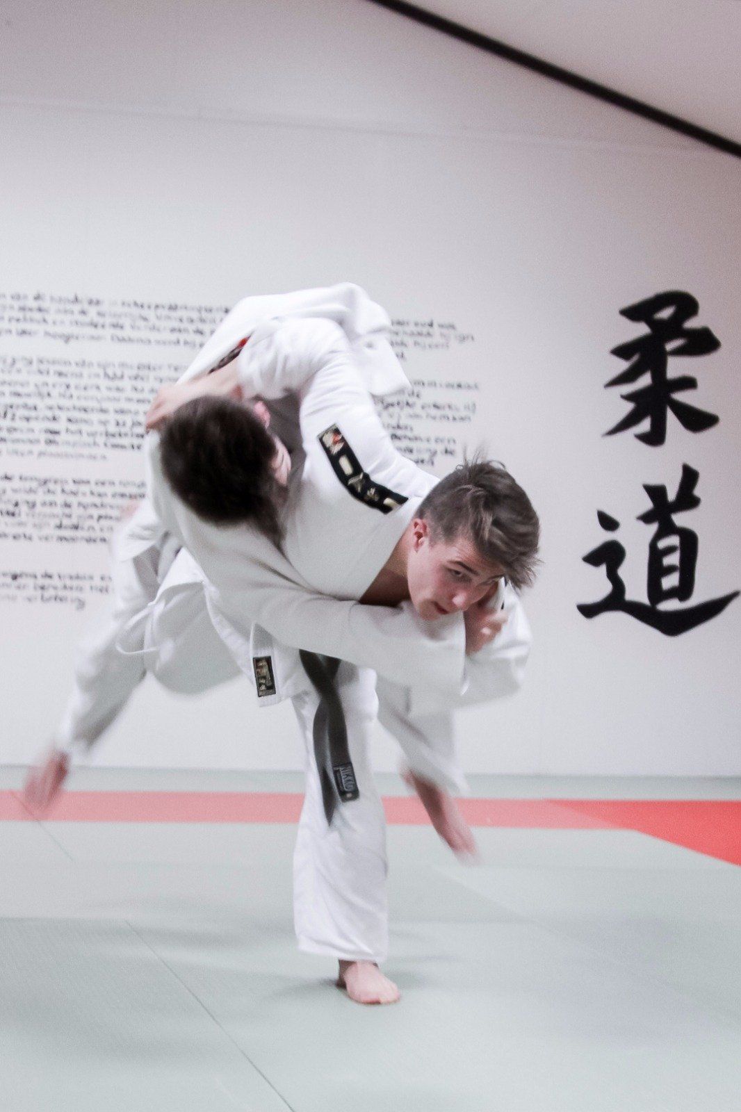 Twee mannen beoefenen judo voor een muur met Chinees schrift