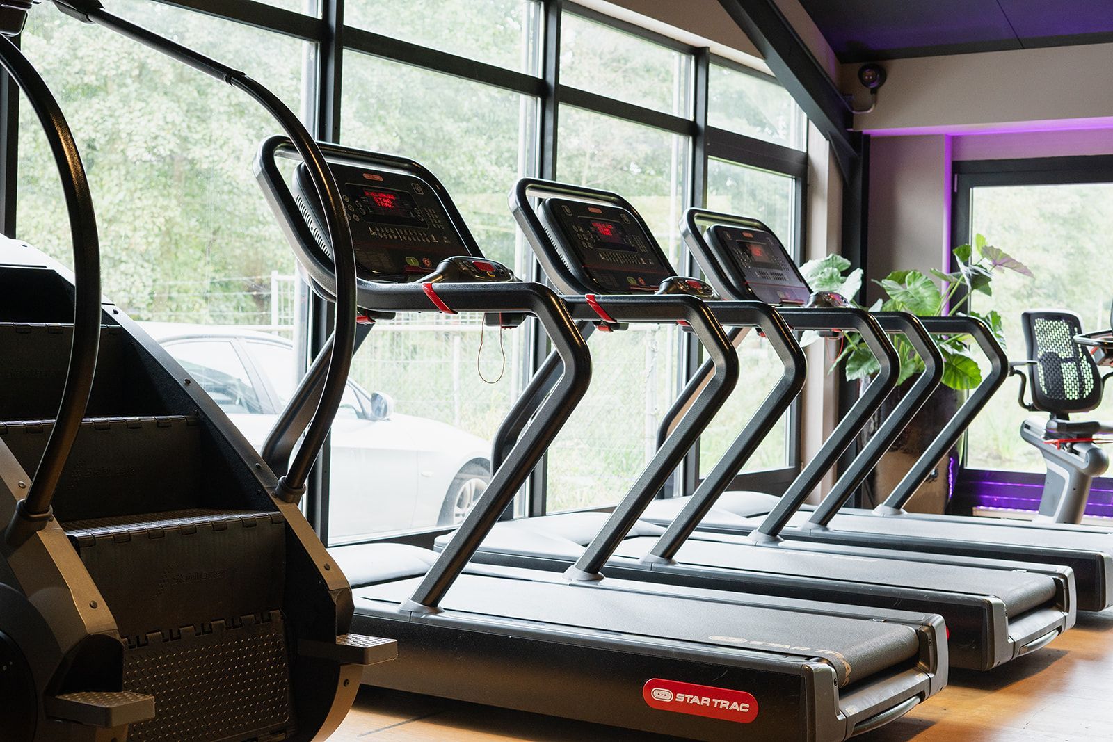 In een sportschool staan een aantal loopbanden op een rij.