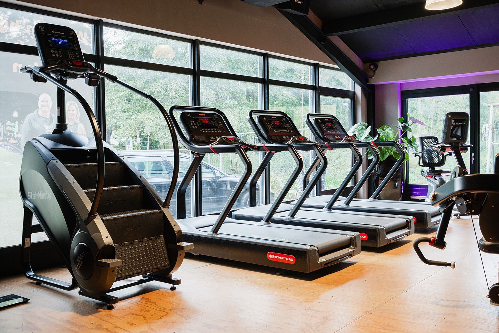 Een rij loopbanden en traplopers in een sportschool.