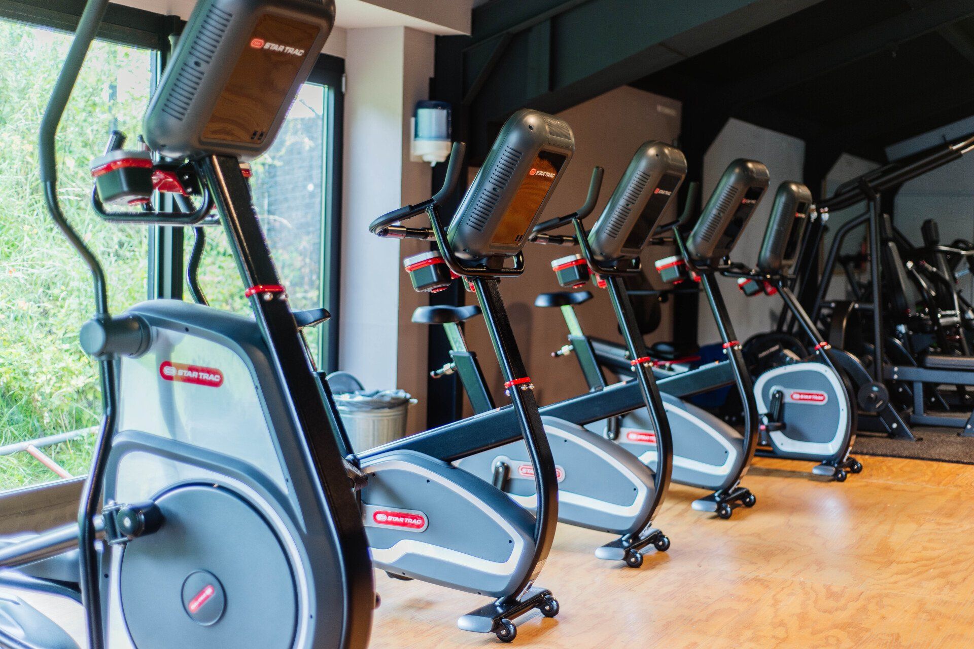 In een sportschool staat een rij hometrainers opgesteld.