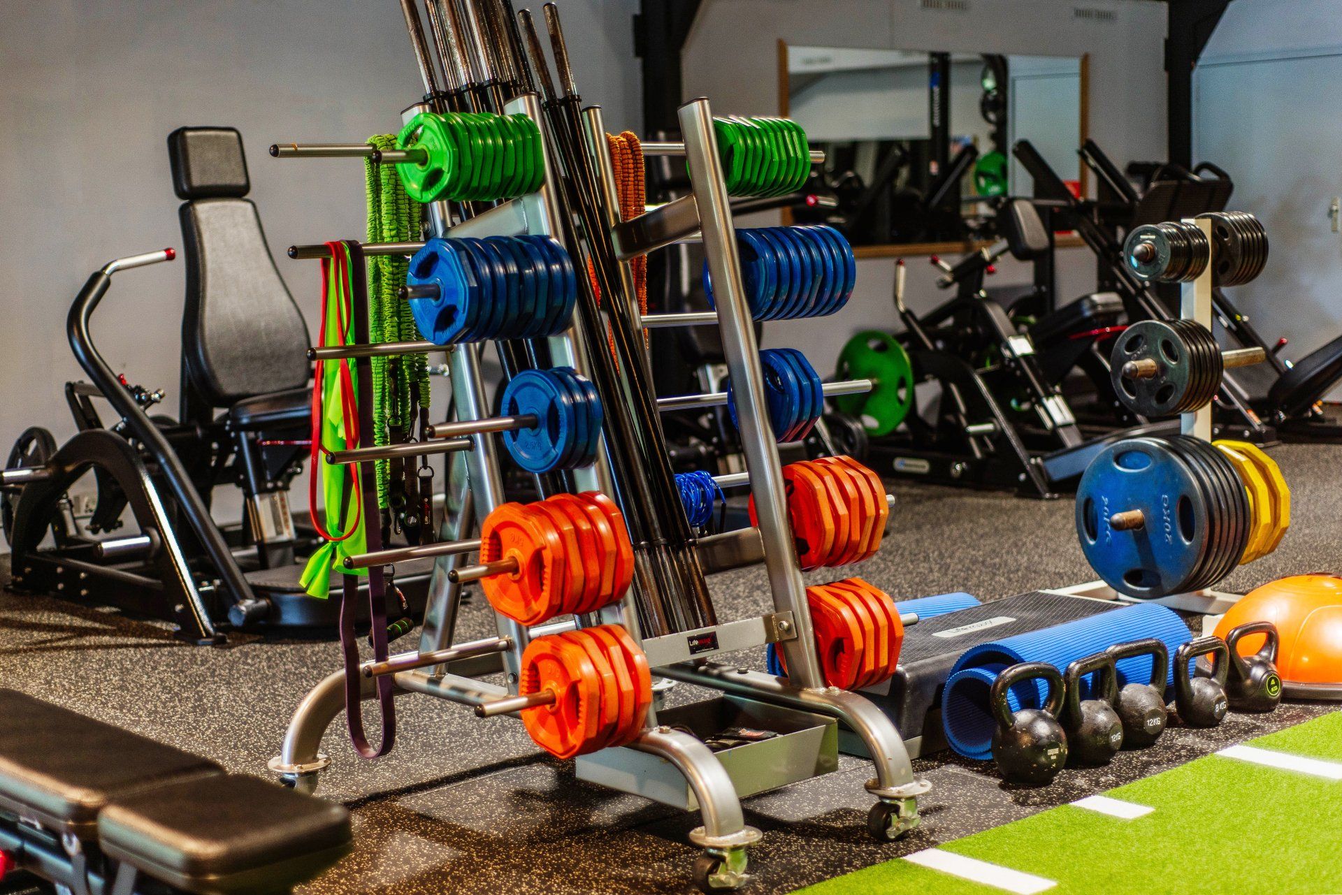 Een sportschool vol met veel fitnessapparatuur en dumbbells.