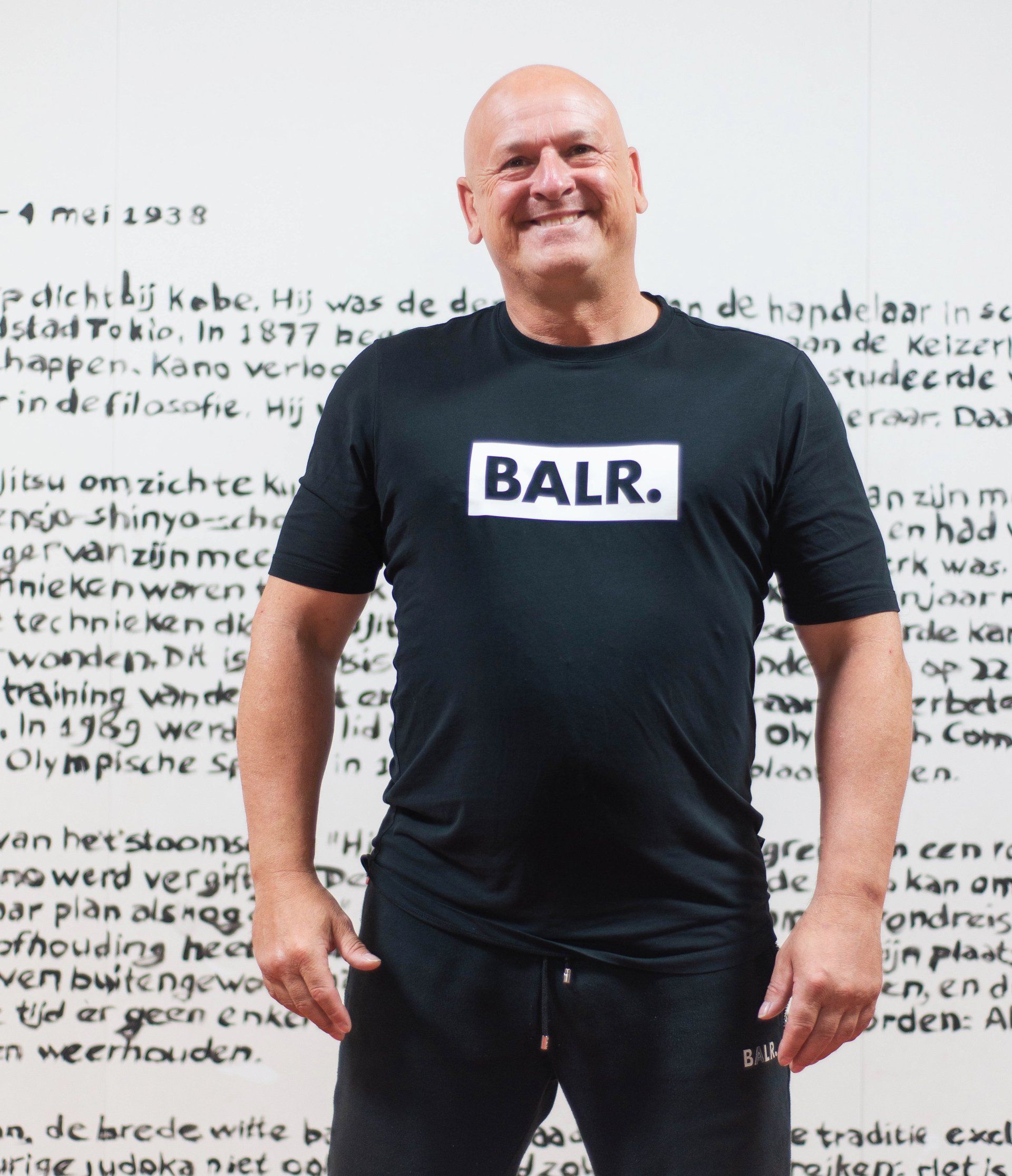 Een kale man, gekleed in een zwart balr-shirt