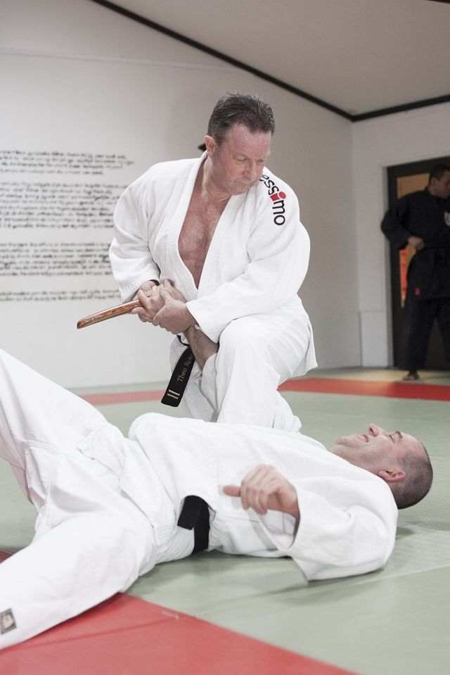Twee mannen beoefenen judo op een mat in een sportschool.