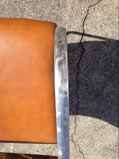 Top-down view of a chair with a brown leather seat and a shiny silver metal frame.