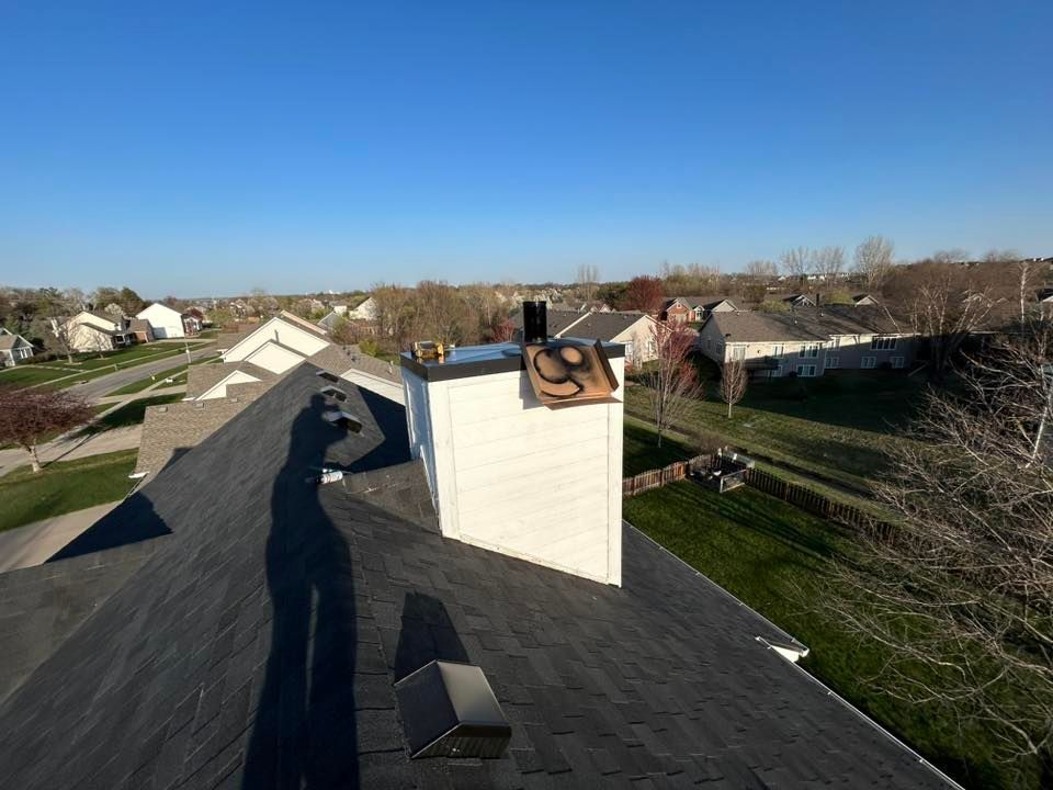 A residential rooftop with a chimney, on a sunny day. Shadow of person taking photo.