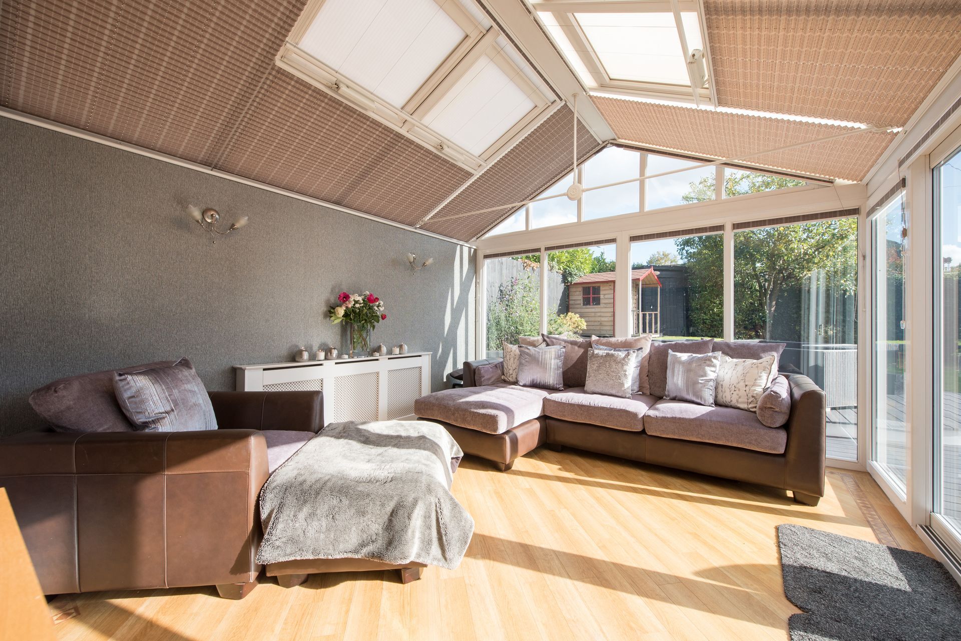 Sunroom with a brown sectional, arm chair, and wood floors; large windows and skylights.