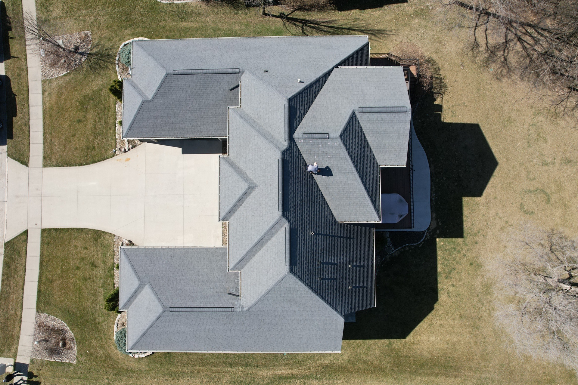 A brick walkway leading to a garage next to a lush green lawn.