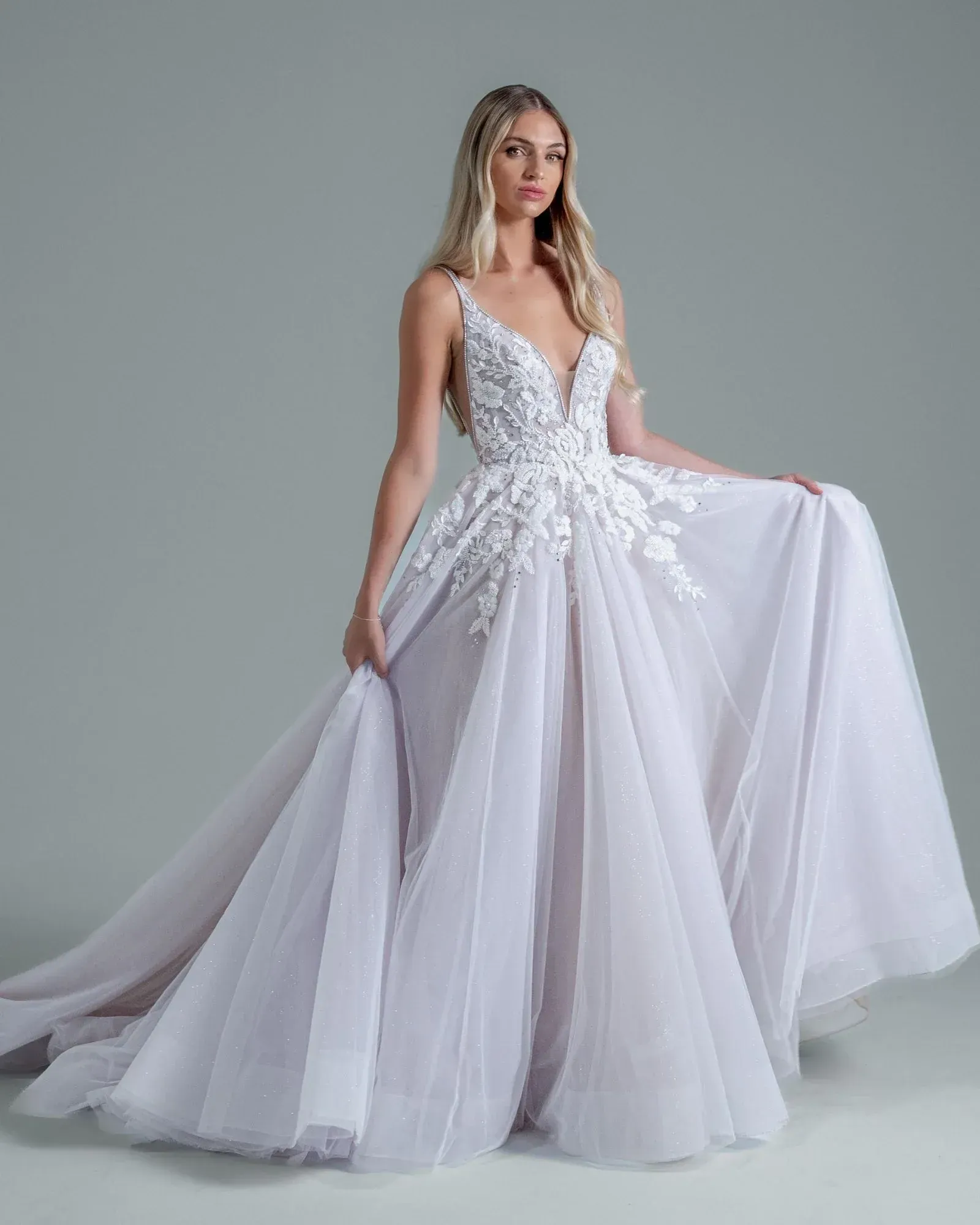 A woman is wearing a white lace wedding dress with long sleeves and a low back.