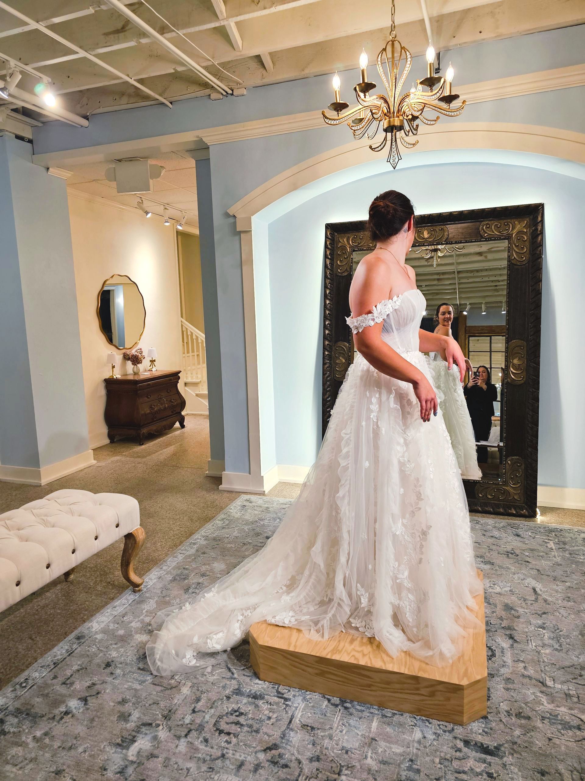 A woman in a wedding dress is standing in front of a mirror.