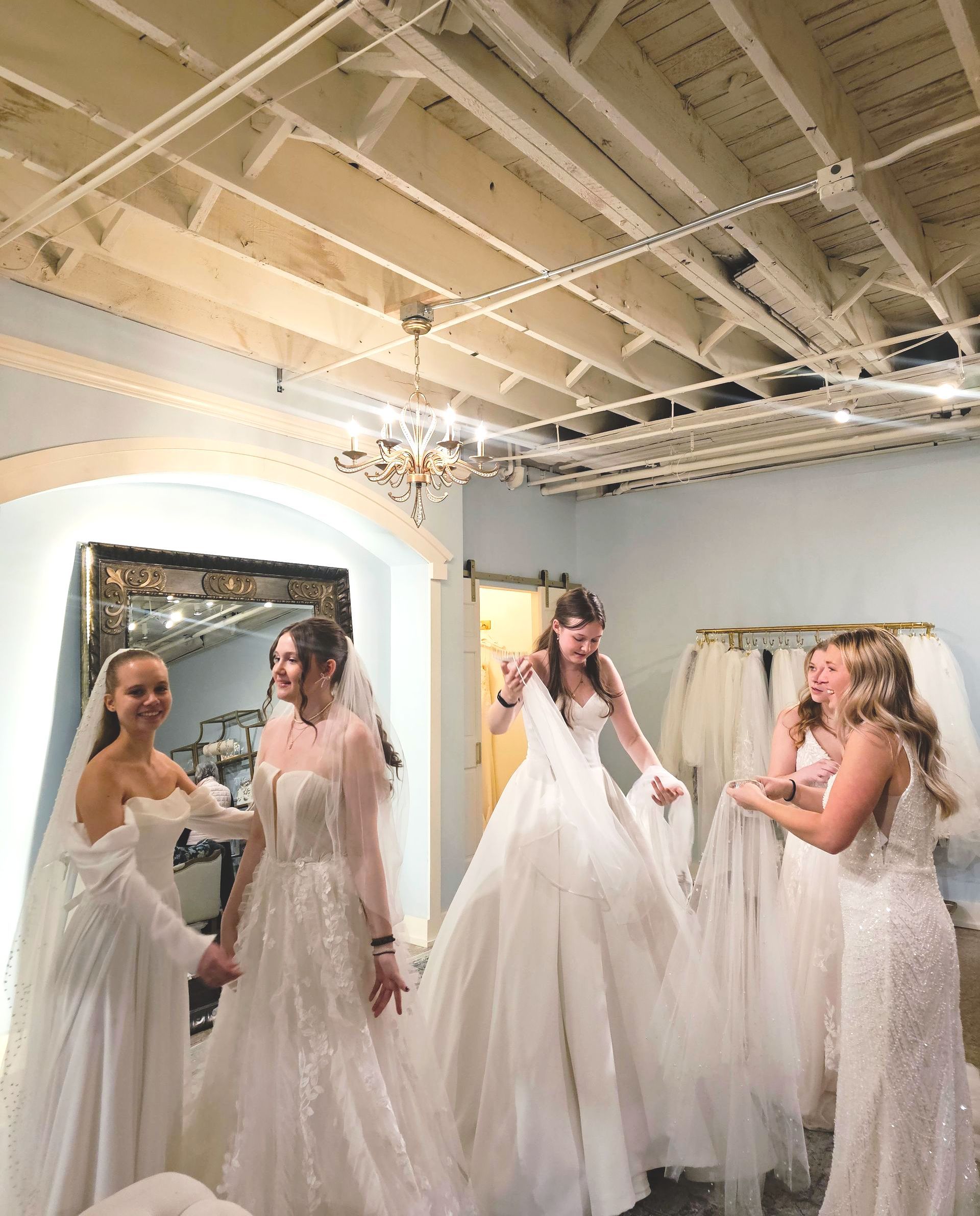A group of women in wedding dresses are standing in a room.