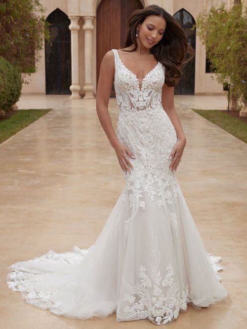 A woman in a white wedding dress is standing in front of a building.