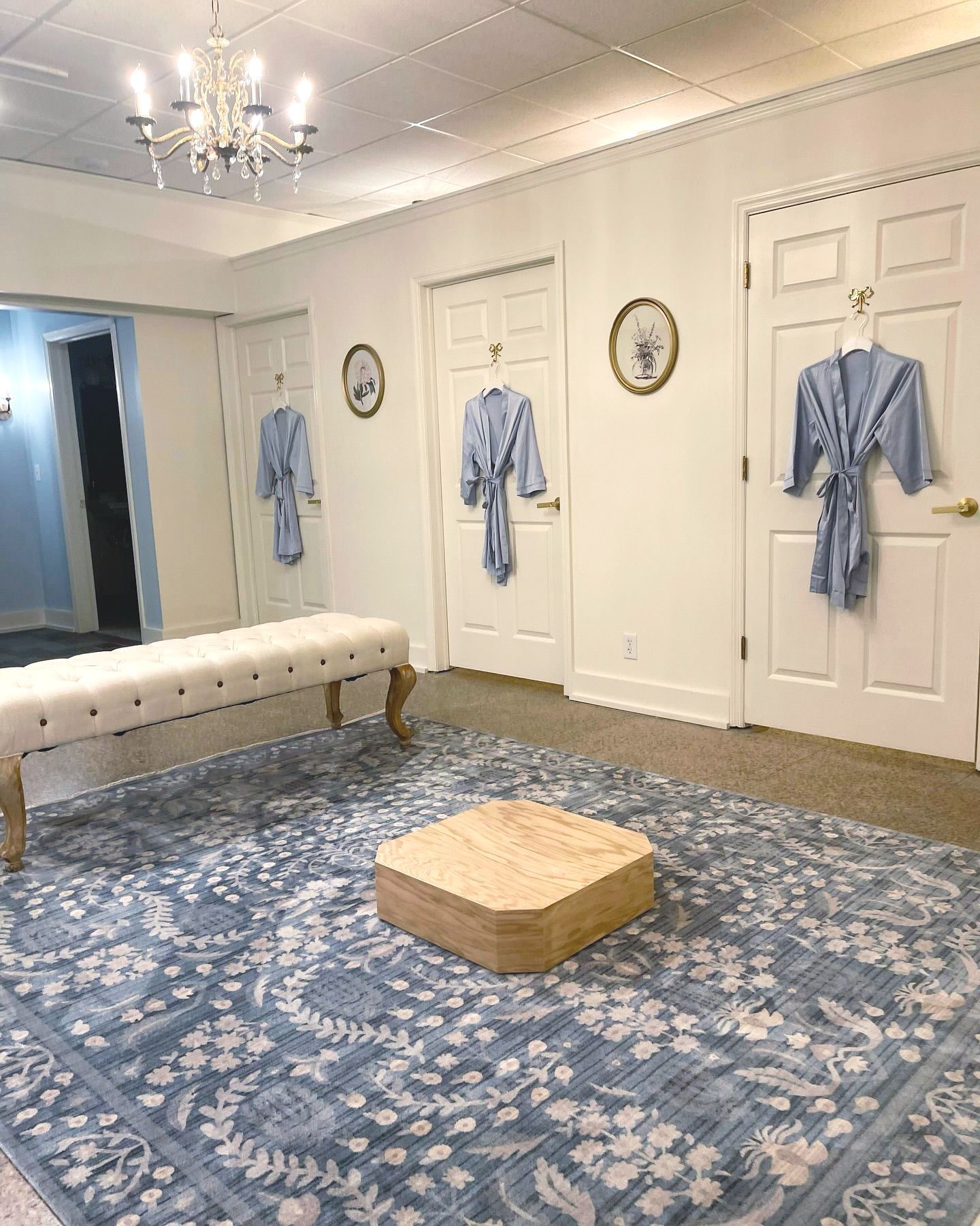 A dressing room with robes hanging on the wall and a bench.