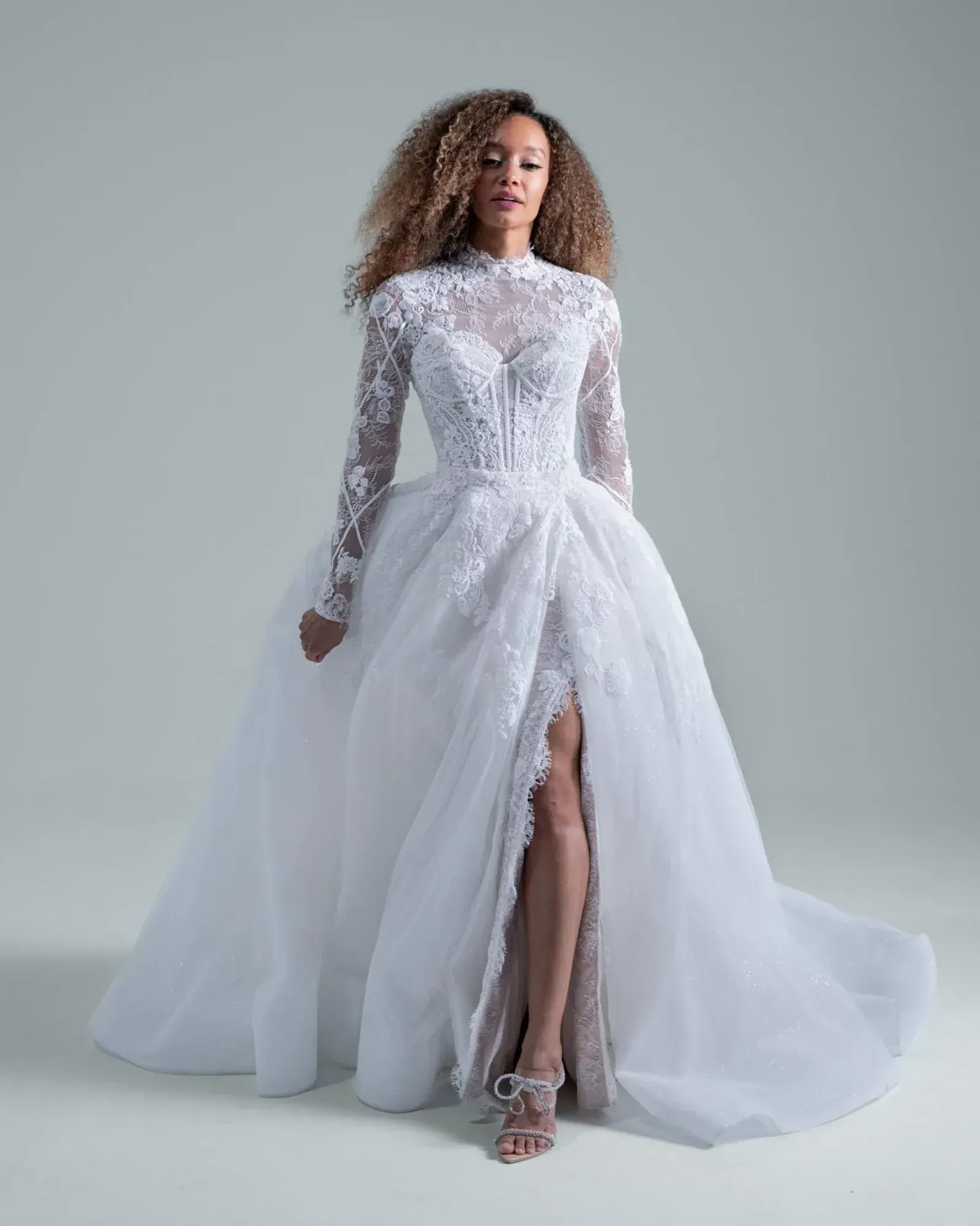 A woman in a white wedding dress is standing in front of a building.