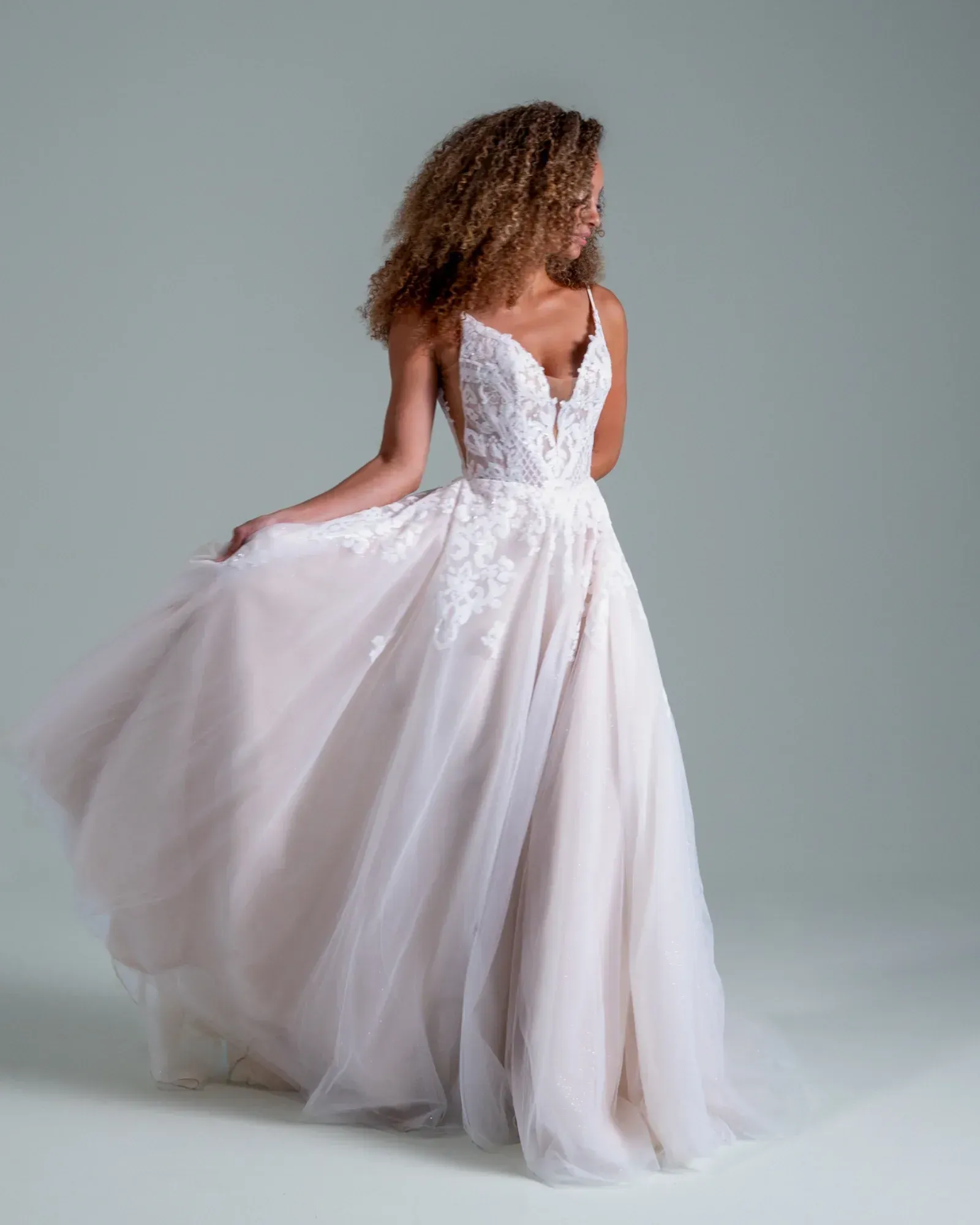 A woman is wearing a white wedding dress and standing on a balcony.
