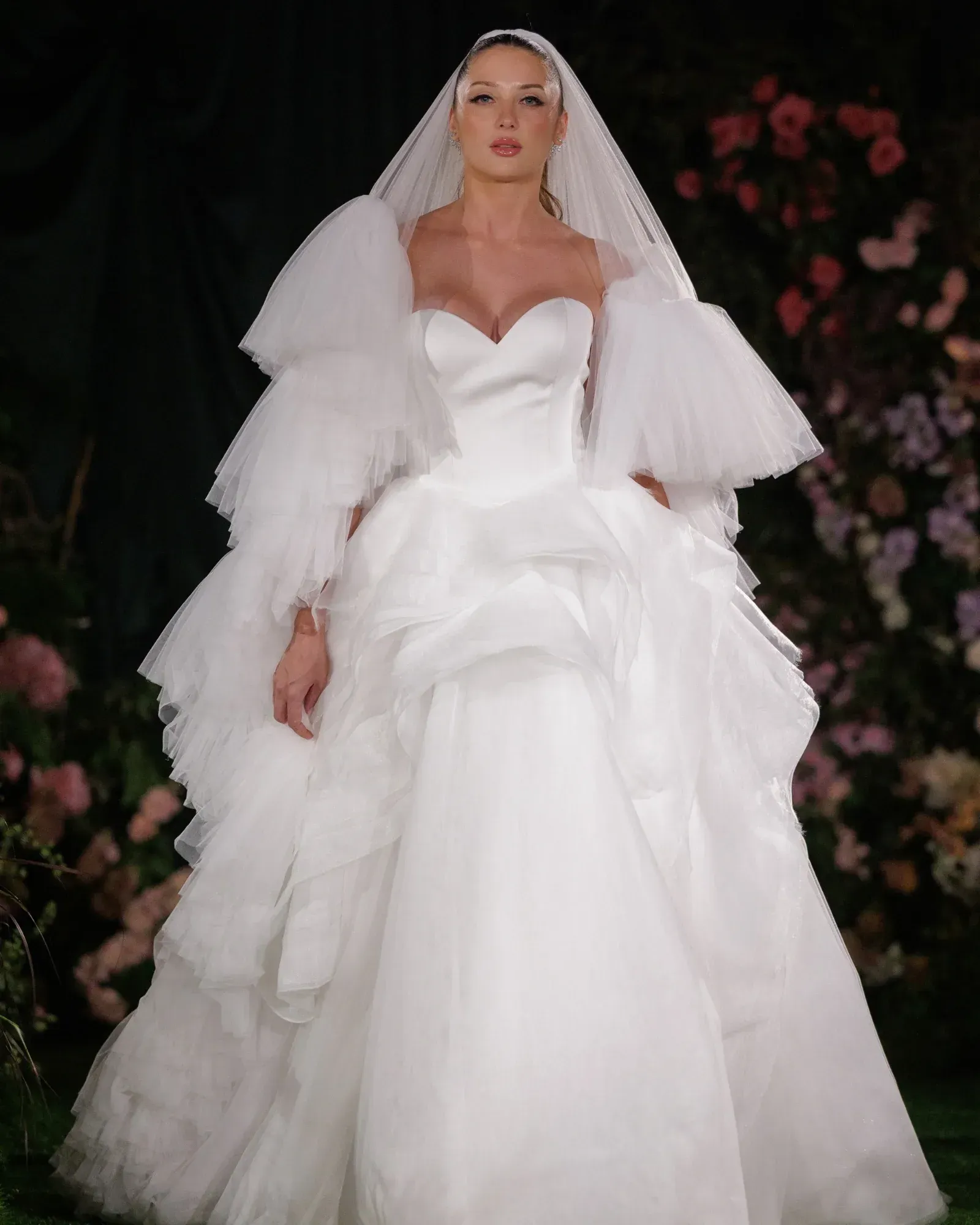 A woman in a white wedding dress is standing on a wooden deck.