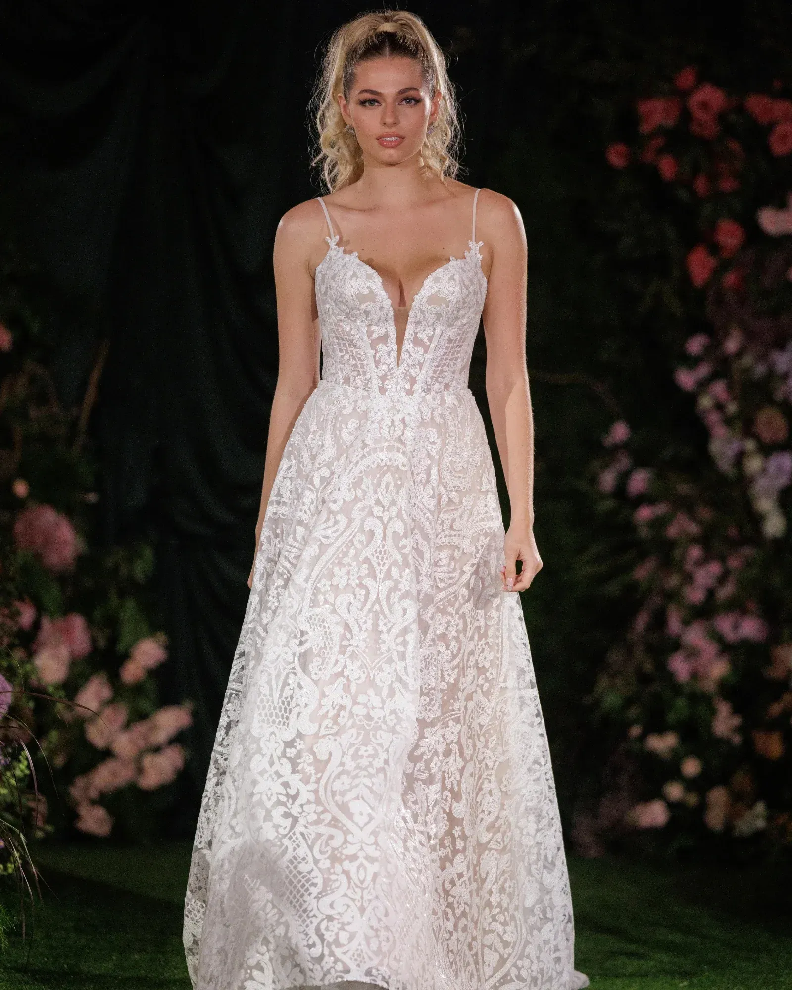 A woman in a white wedding dress is standing in front of a building.