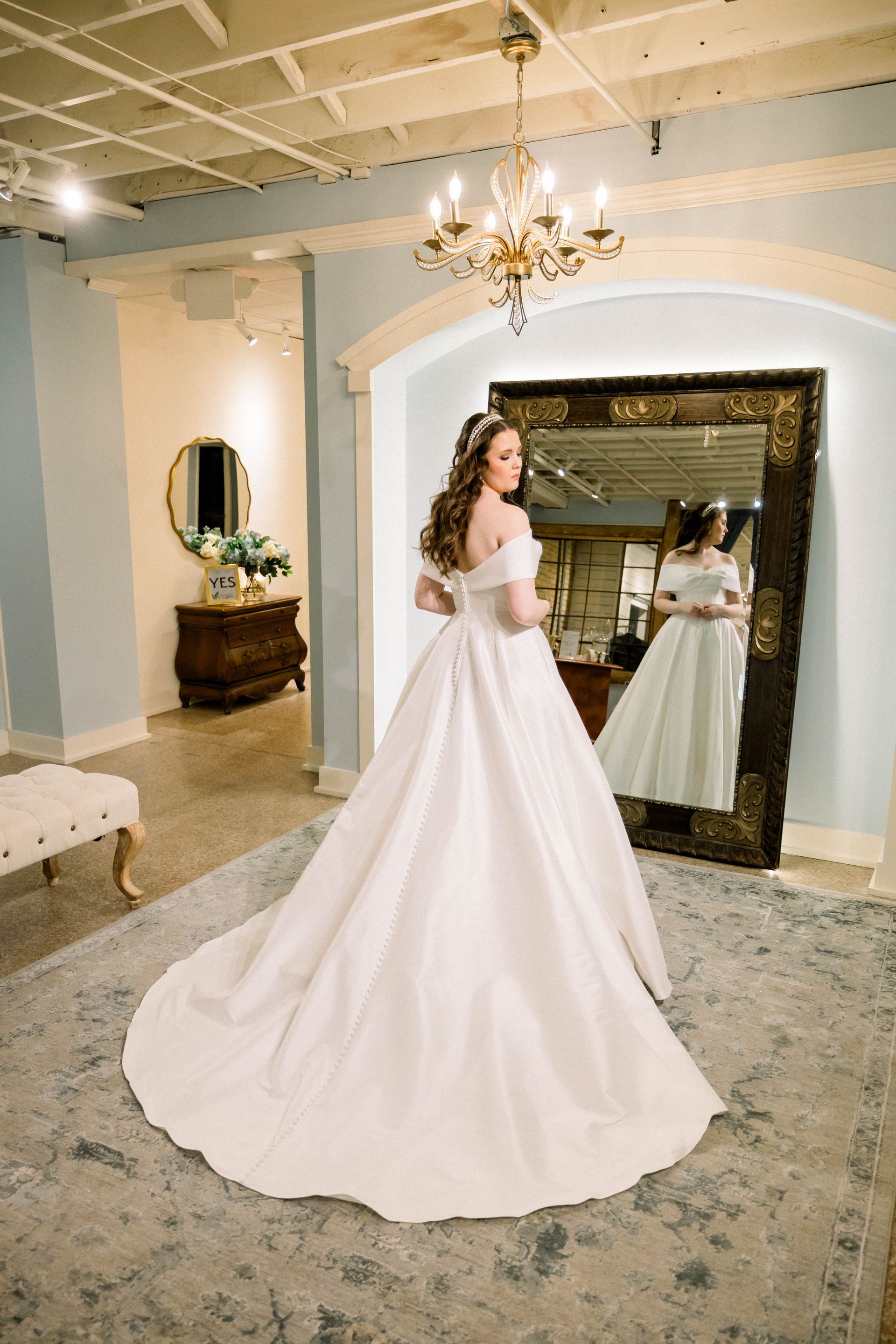 A woman in a white wedding dress is standing on a wooden deck.