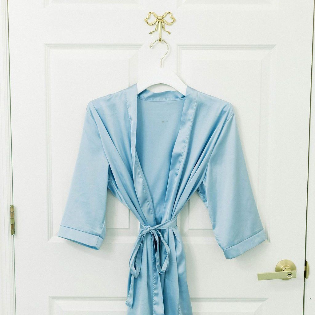 A light blue robe is hanging on a white door