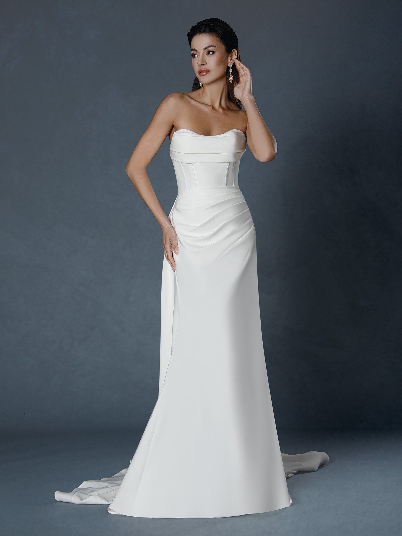 A woman is wearing a white strapless wedding dress
