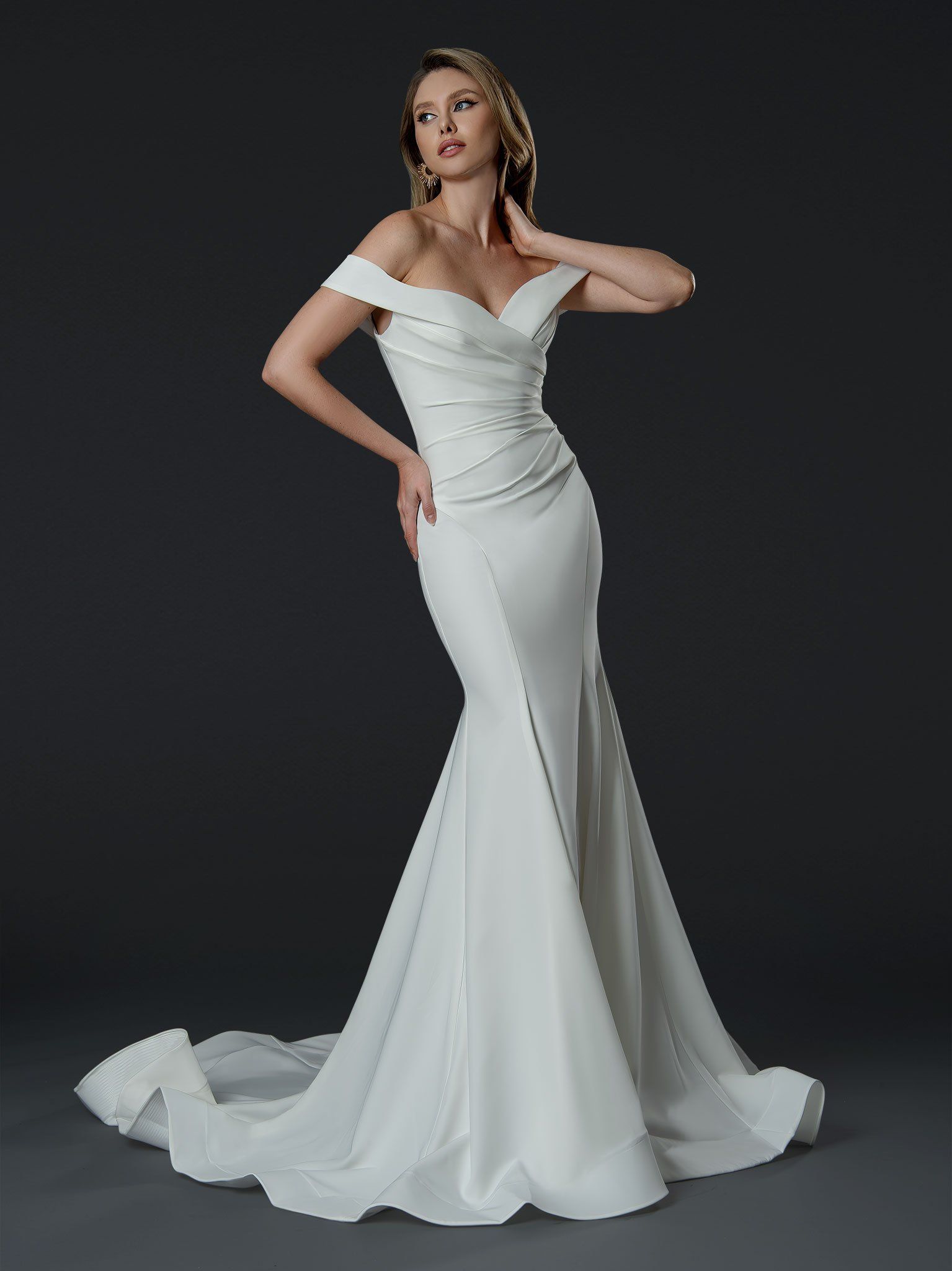 A woman is wearing a white off the shoulder wedding dress.