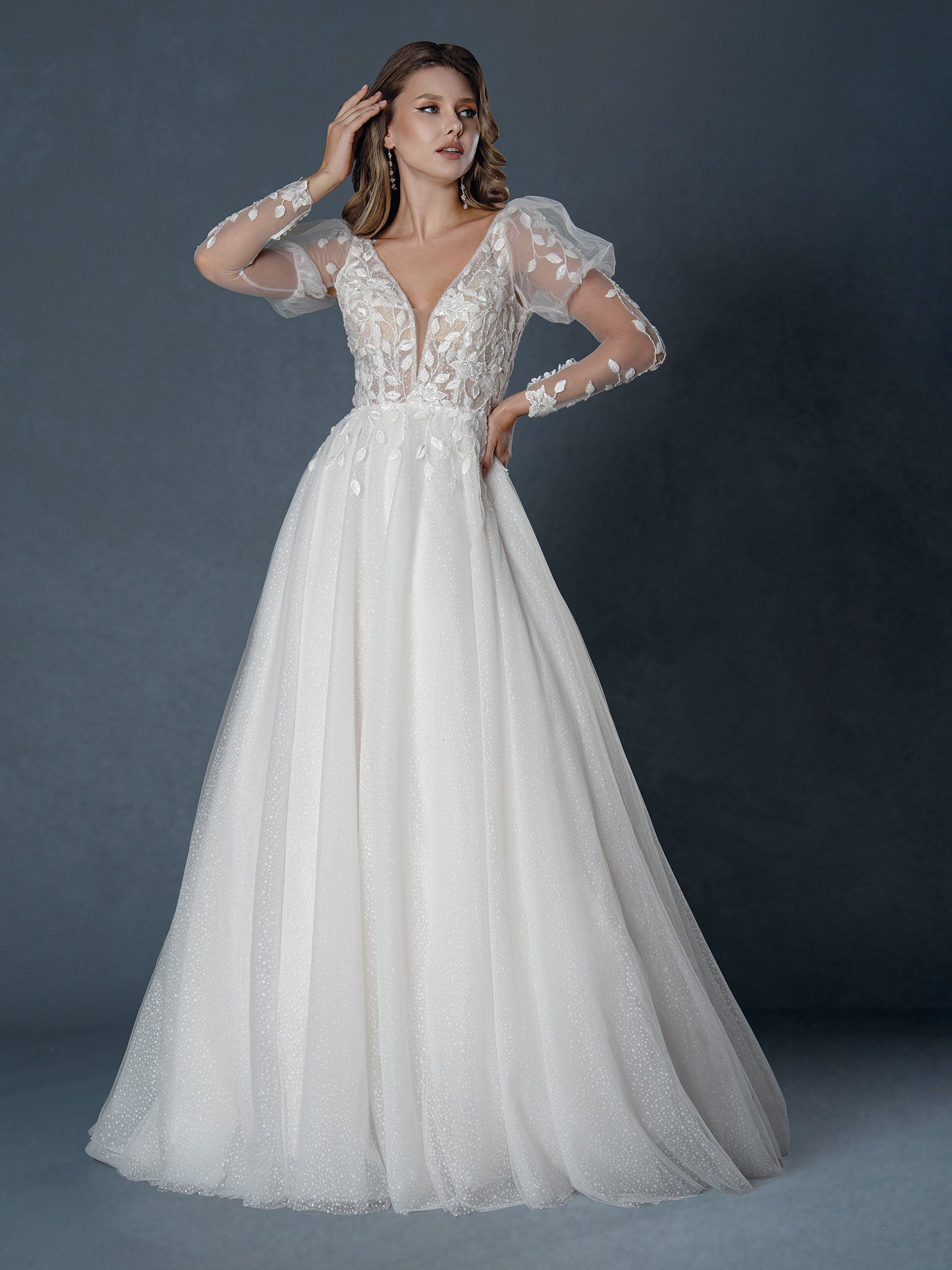 A woman is wearing a white wedding dress with long sleeves.