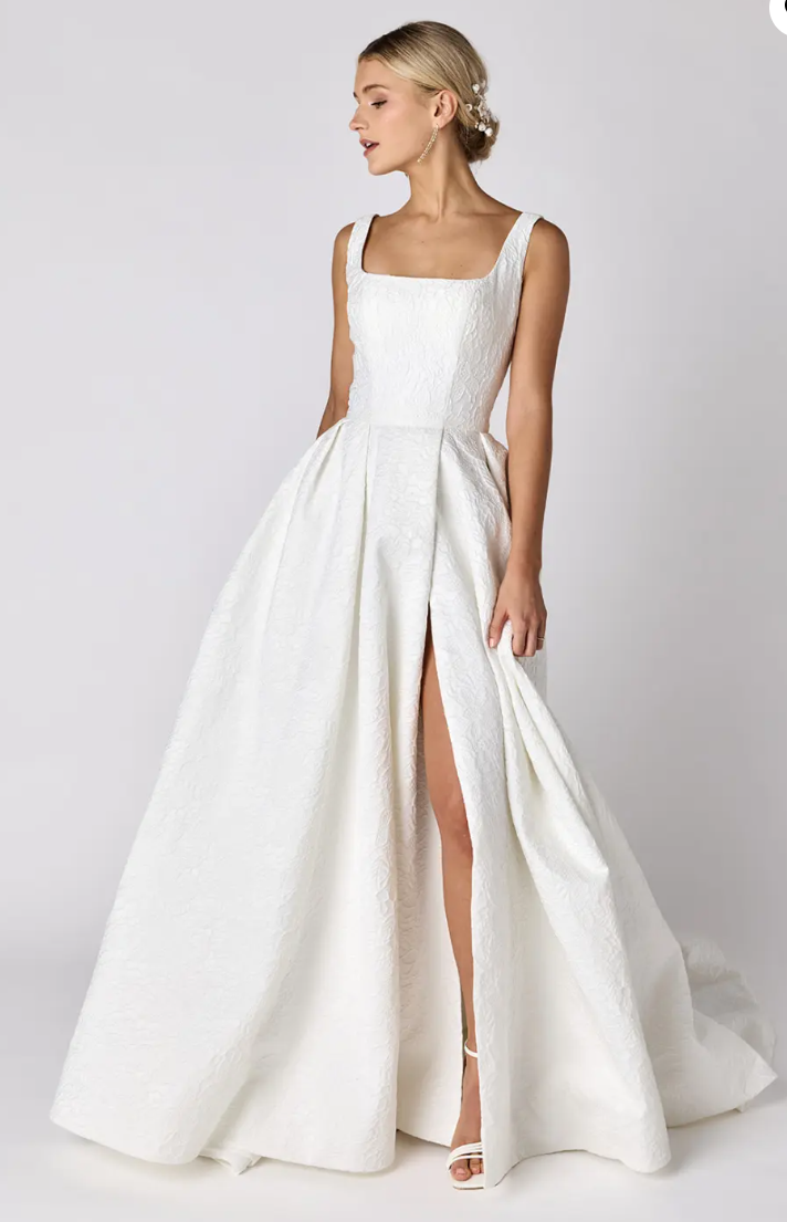A woman is wearing a white wedding dress with a high slit.