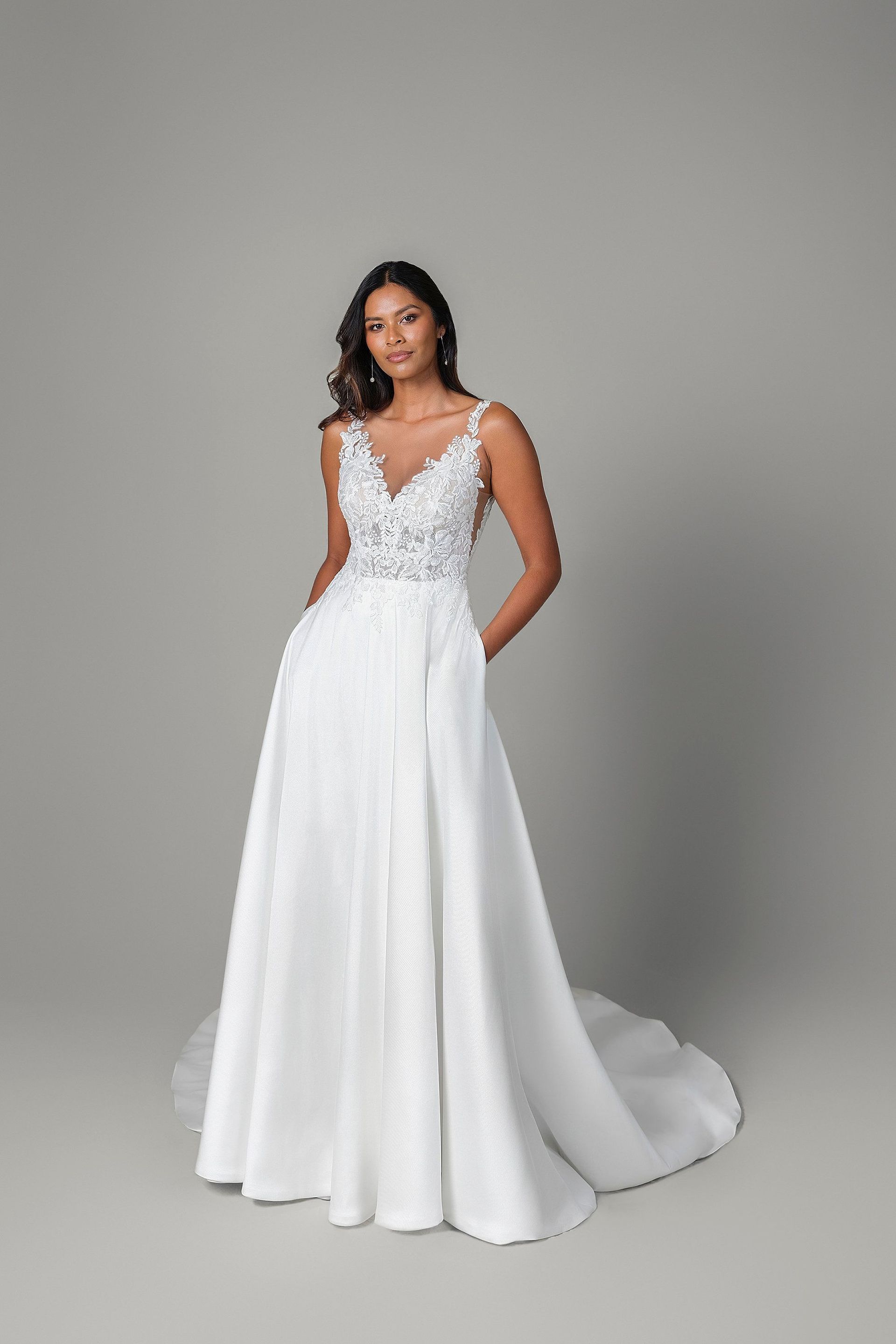 A woman is wearing a white wedding dress with pockets.