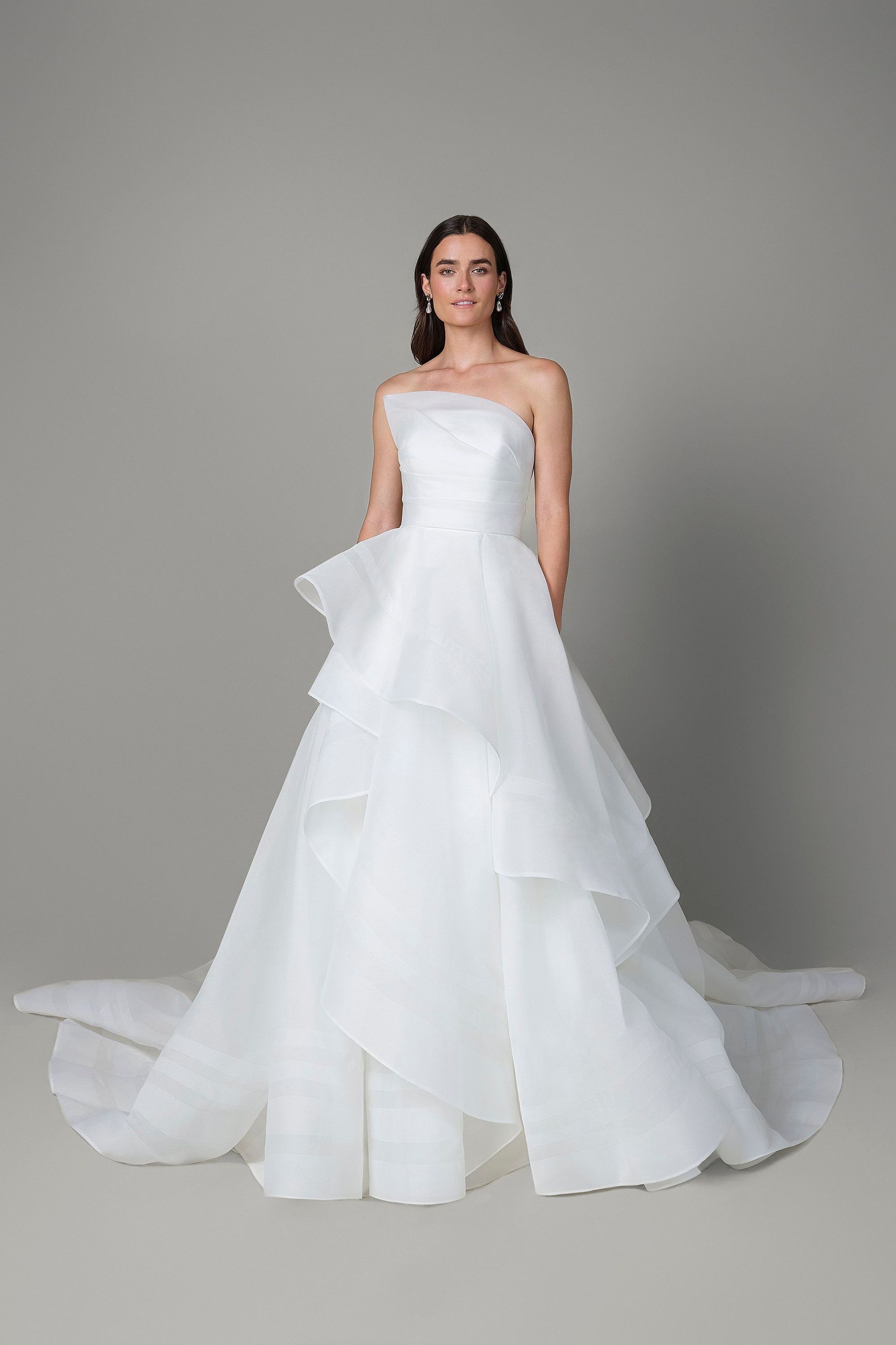 A woman is wearing a white strapless wedding dress.