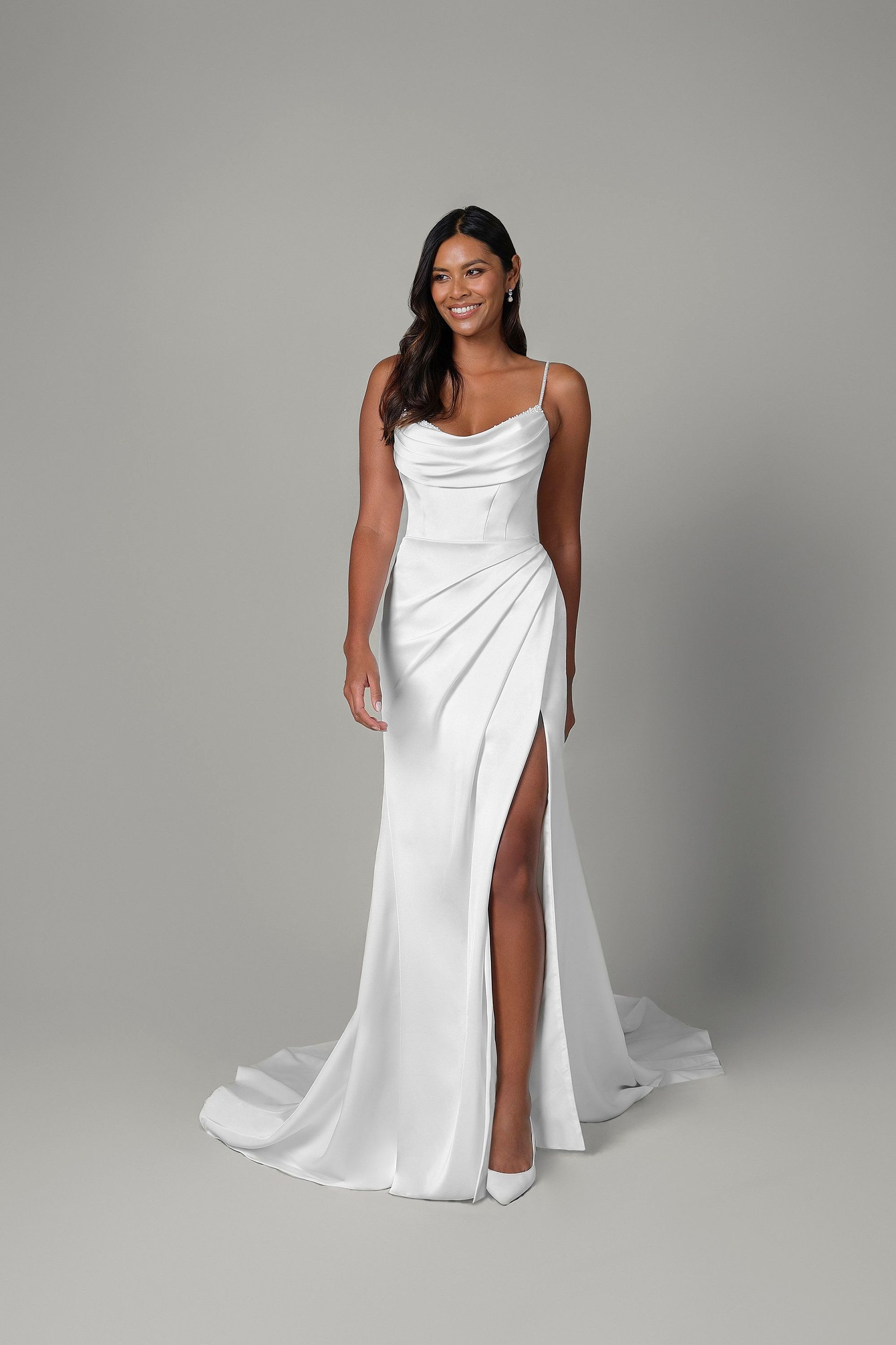 A woman is wearing a white wedding dress with a high slit.