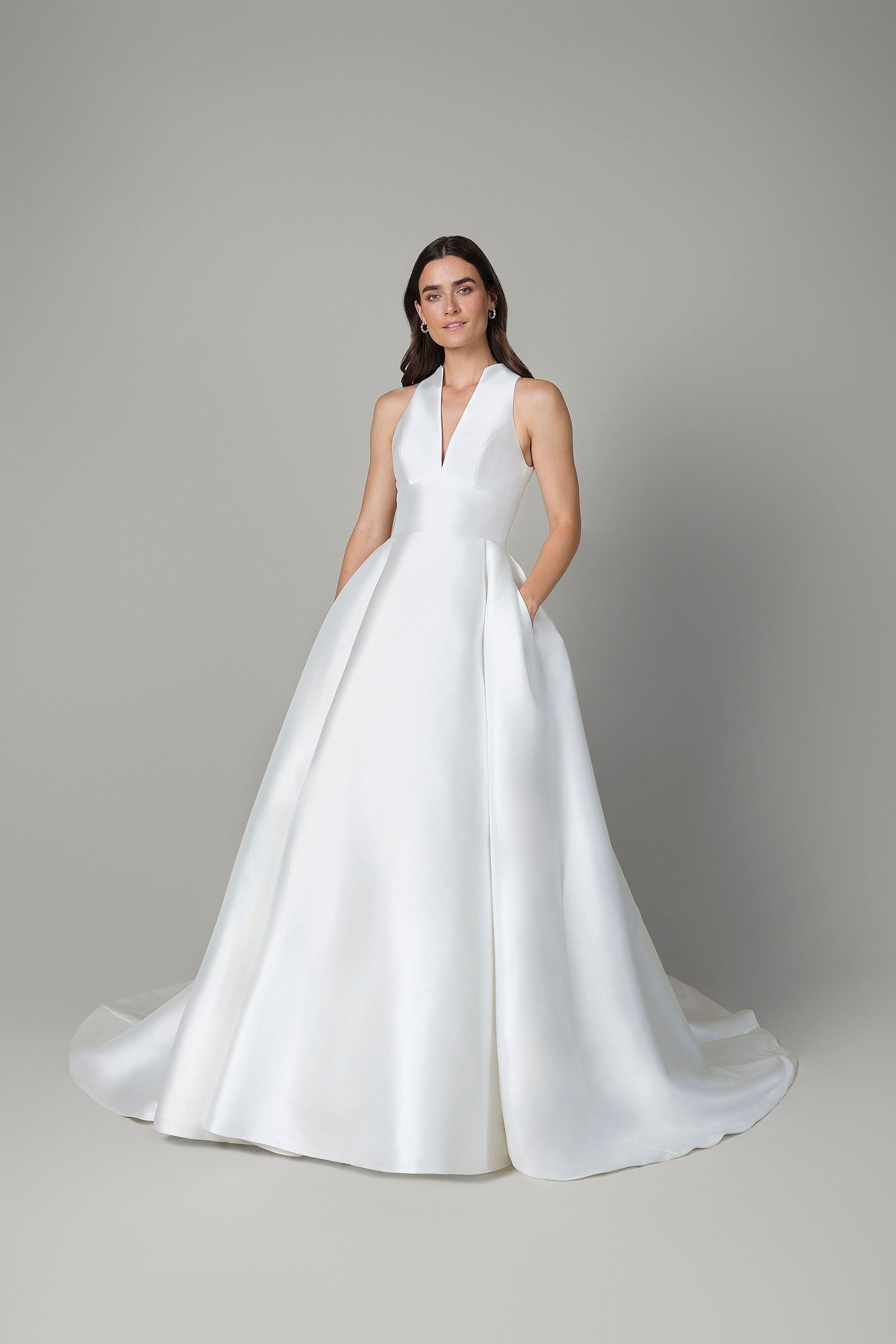 A woman is wearing a white wedding dress with pockets.