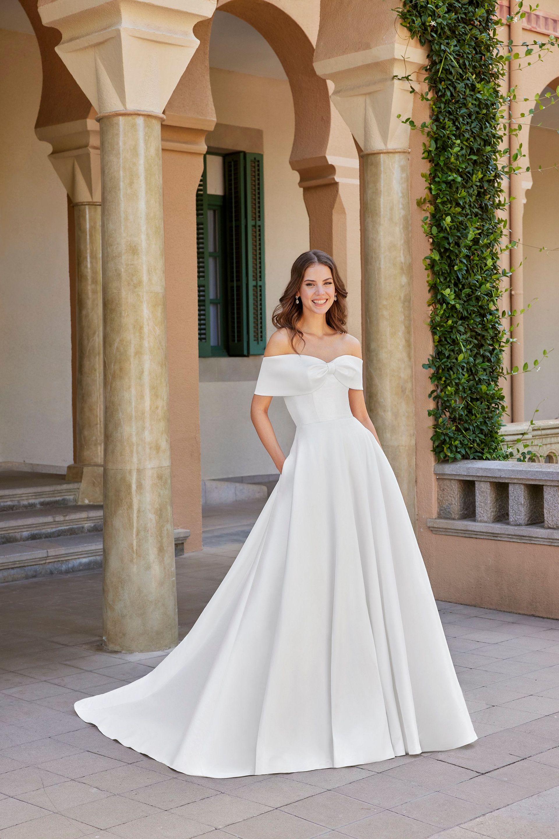 A woman in a white wedding dress is standing in front of a building.