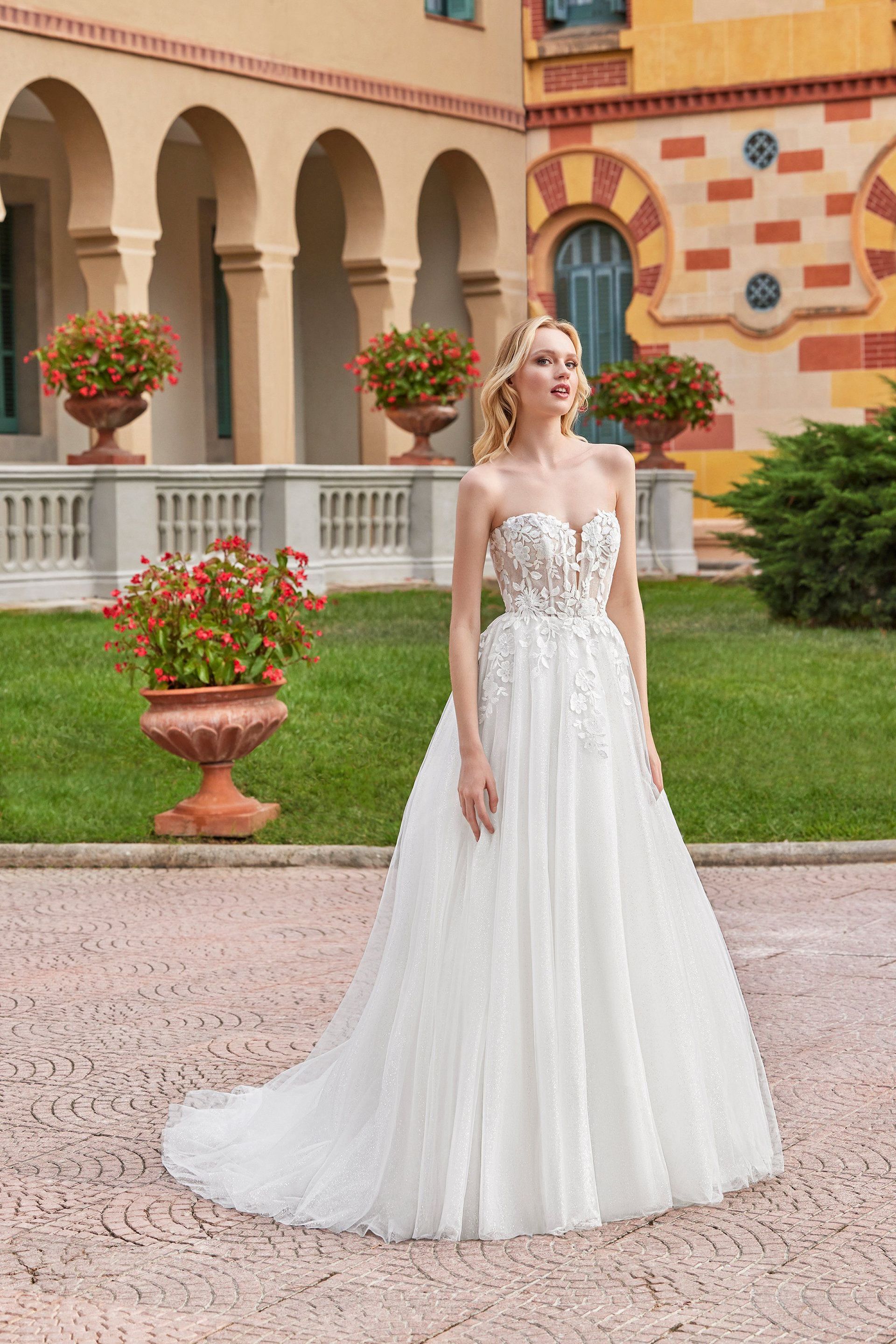 A woman in a white wedding dress is standing in front of a building.