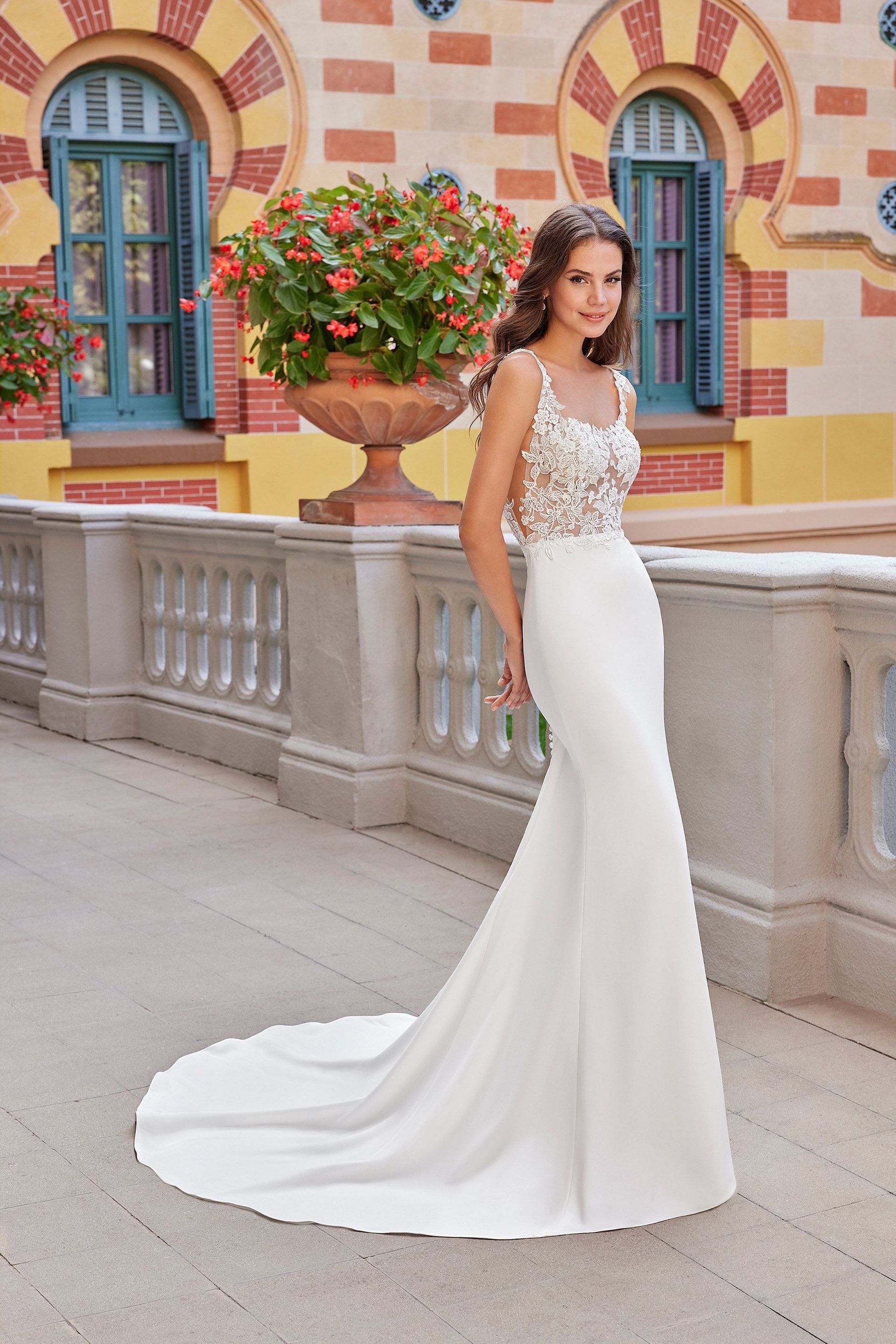 A woman in a white wedding dress is standing in front of a building.