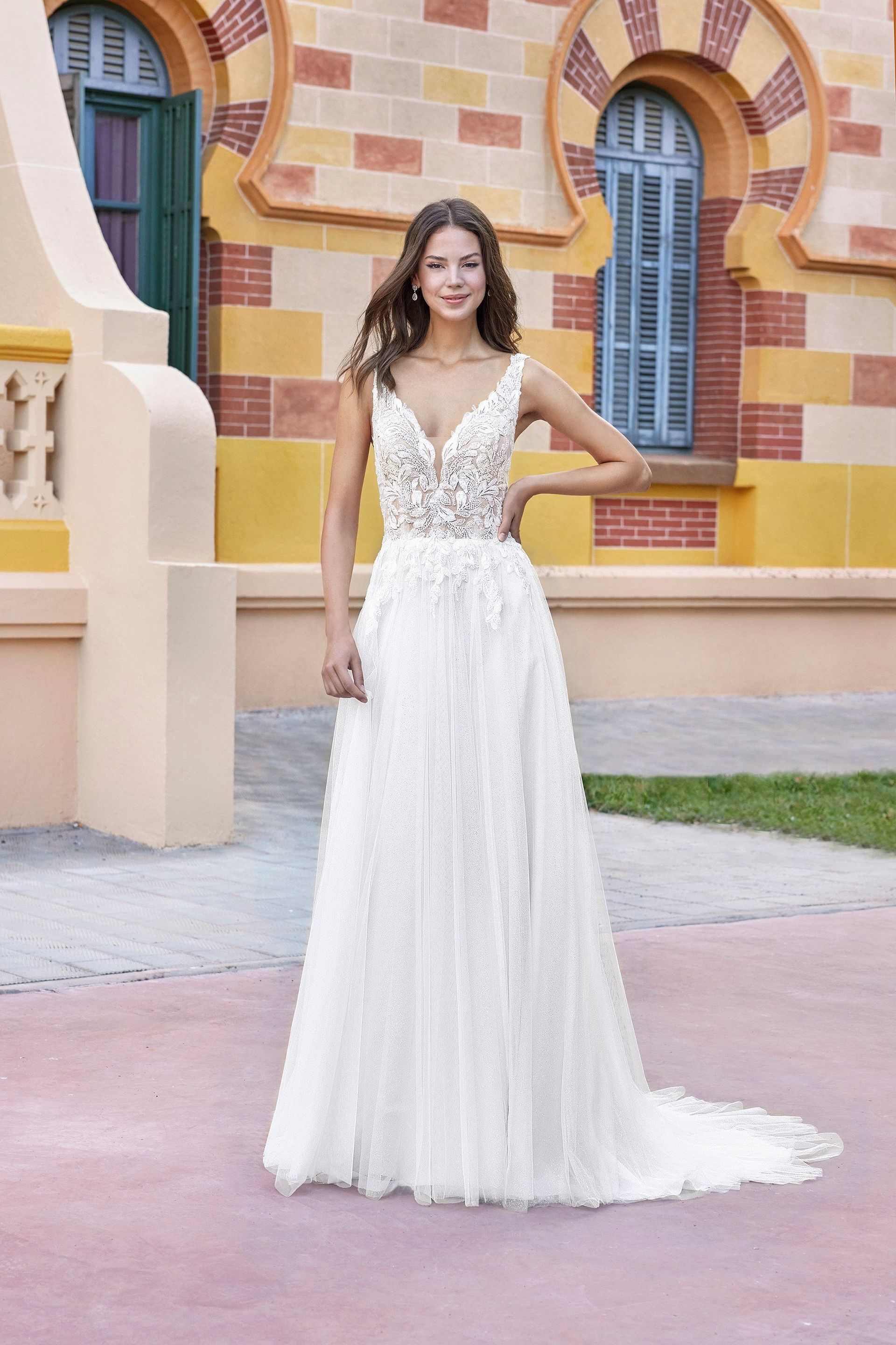 A woman in a white wedding dress is standing in front of a building.