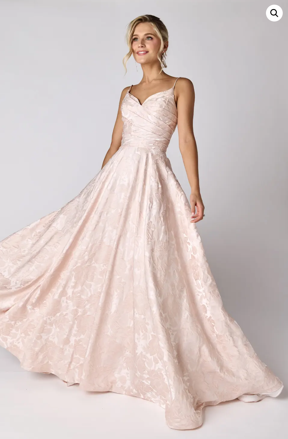 A woman in a long pink dress is standing on a white background.