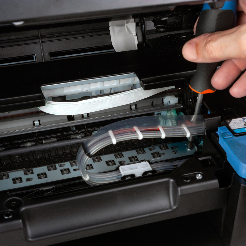 A person is fixing a printer with a screwdriver