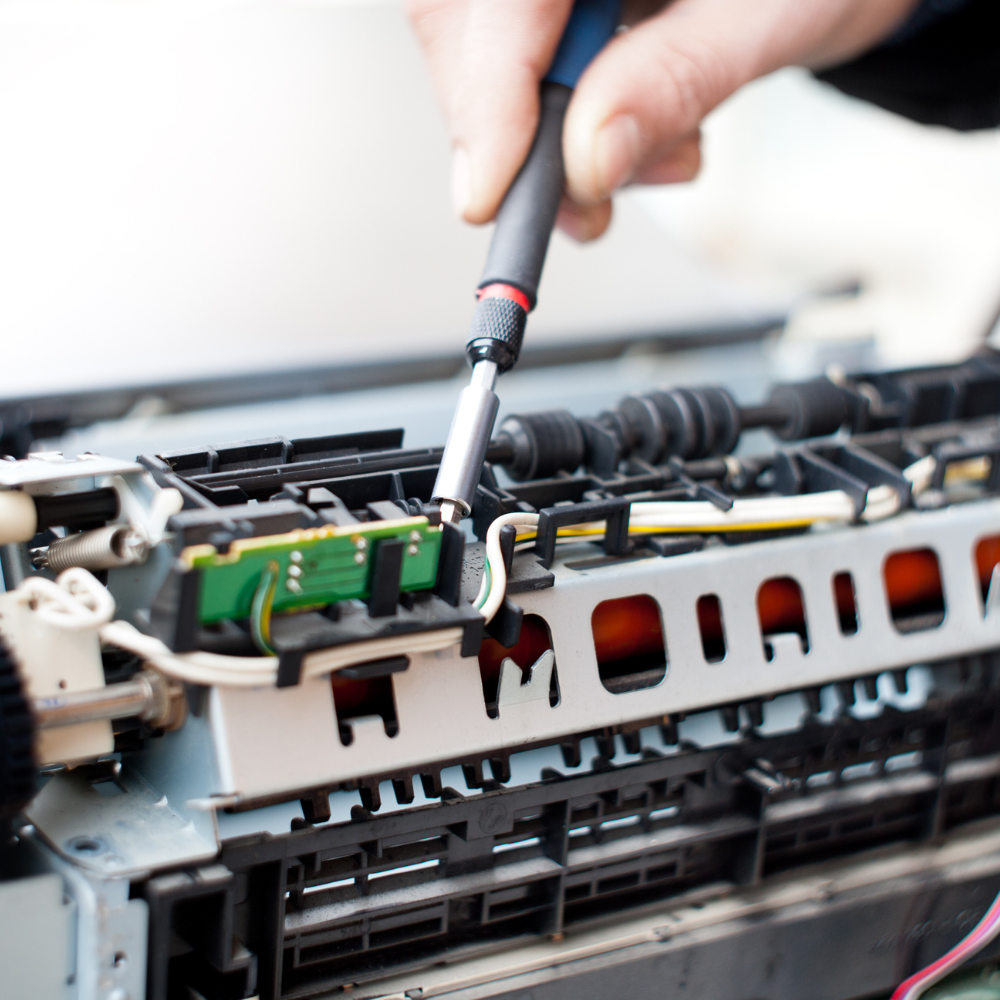 A person is fixing a printer with a screwdriver