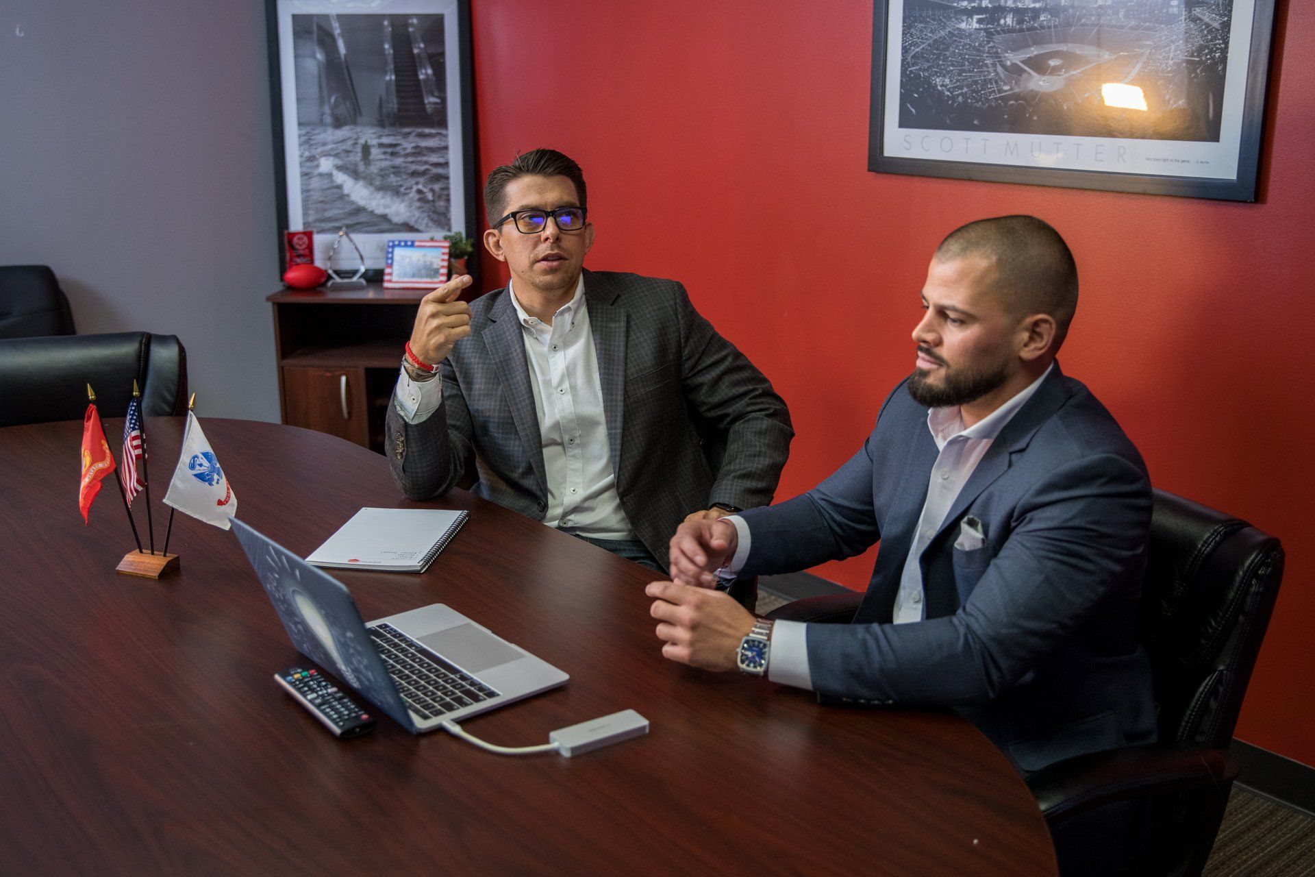 Two men are sitting at a table with a laptop on it