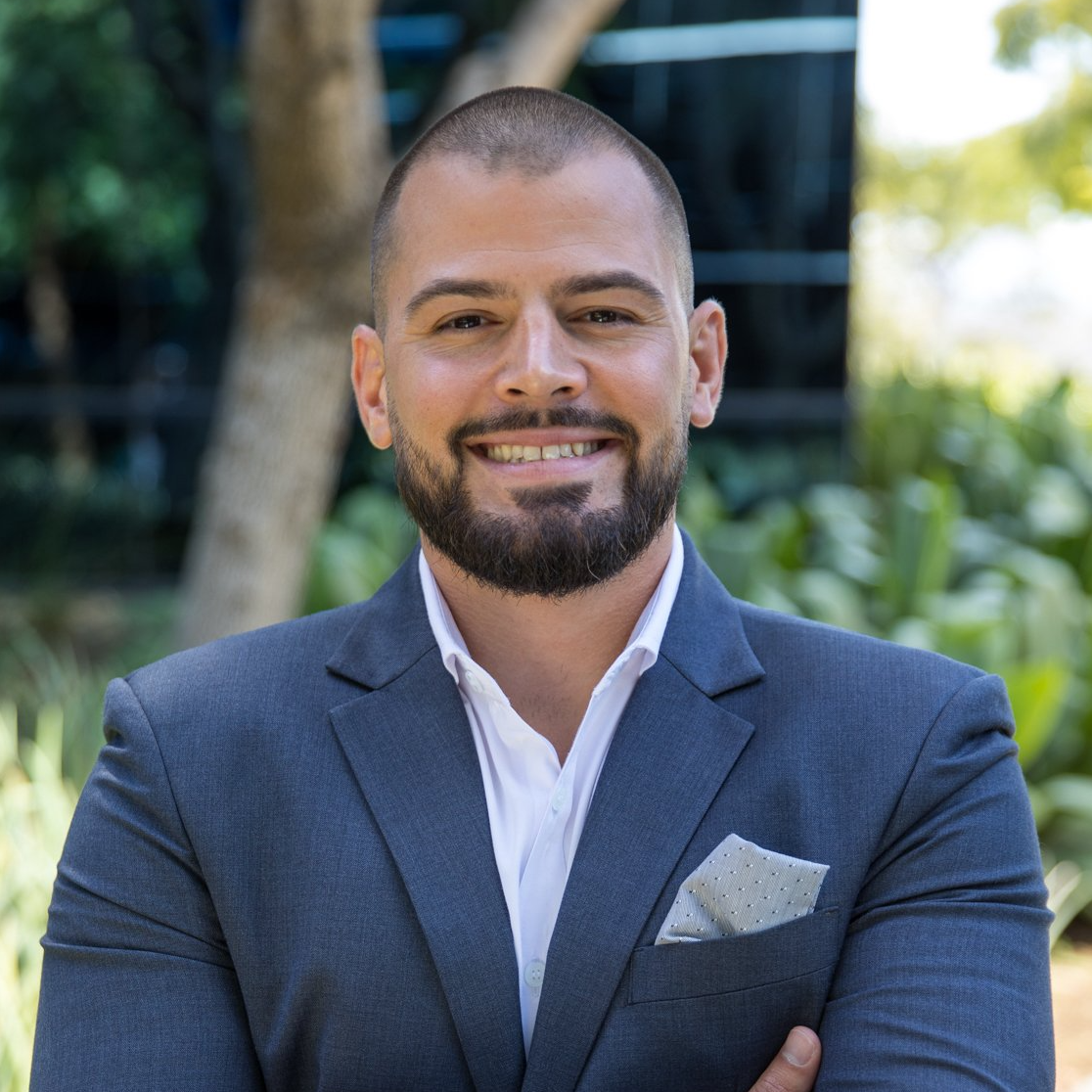 A man with a beard is wearing a suit and smiling for the camera.