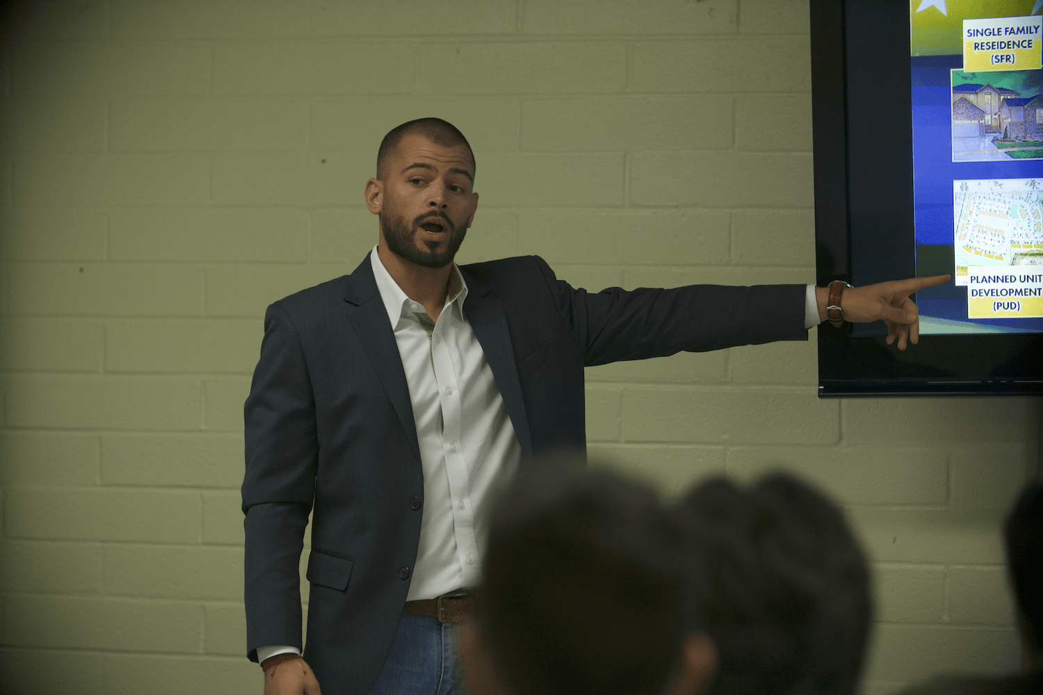 A man in a suit is giving a presentation to a group of people